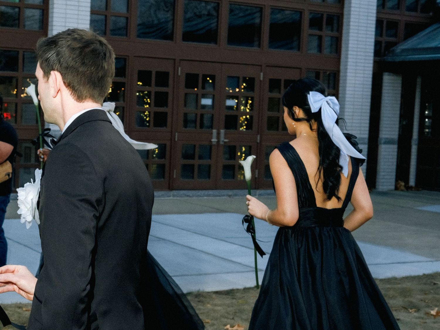 Wedding party in black and white attire poses together at sunset in front of a building.