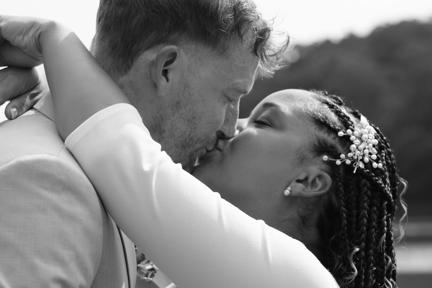 Black and white romantic wedding photo showing a tender kiss between newlyweds, with bride wearing delicate floral hair accessories.