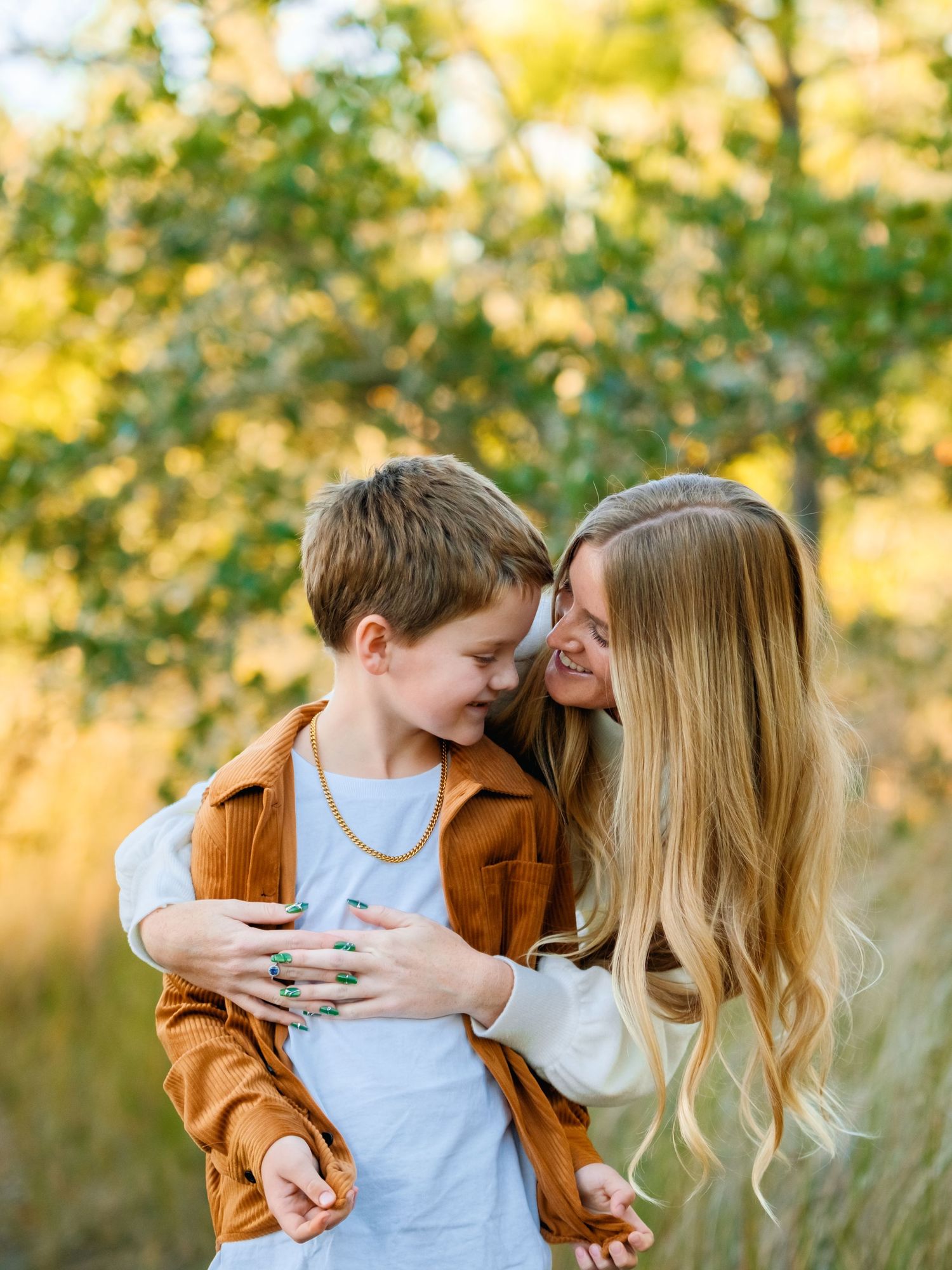A tender family moment captured in golden sunlight with a mother and child sharing affectionate embraces in an outdoor setting.
