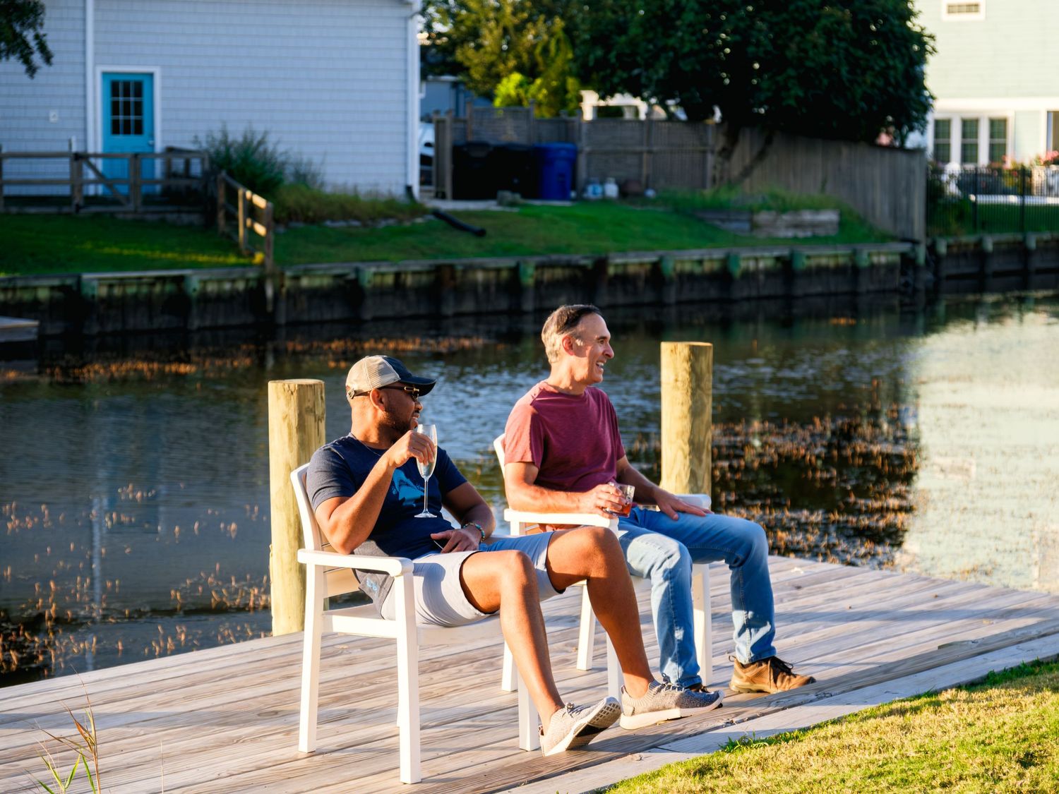 Three people relax on a wooden dock by a peaceful lake while enjoying the summer afternoon.
