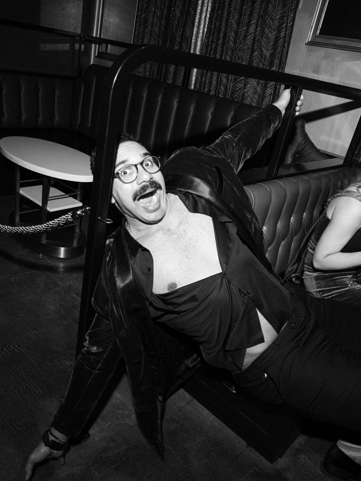 A black and white photo sequence shows someone in dark clothing reclining and posing dramatically against a dark background.