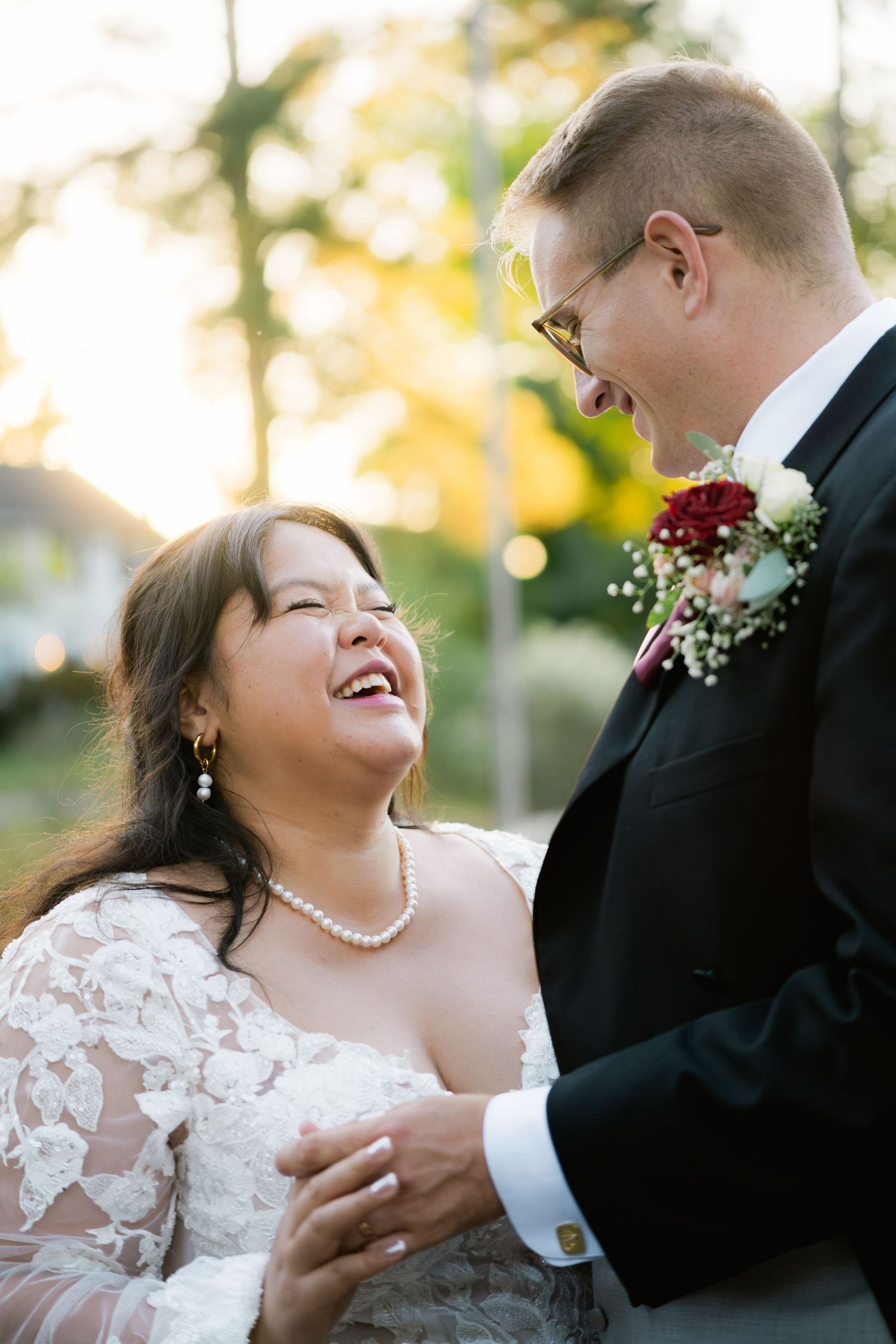 A wedding couple shares a joyful dance moment together outdoors during golden hour photography session.