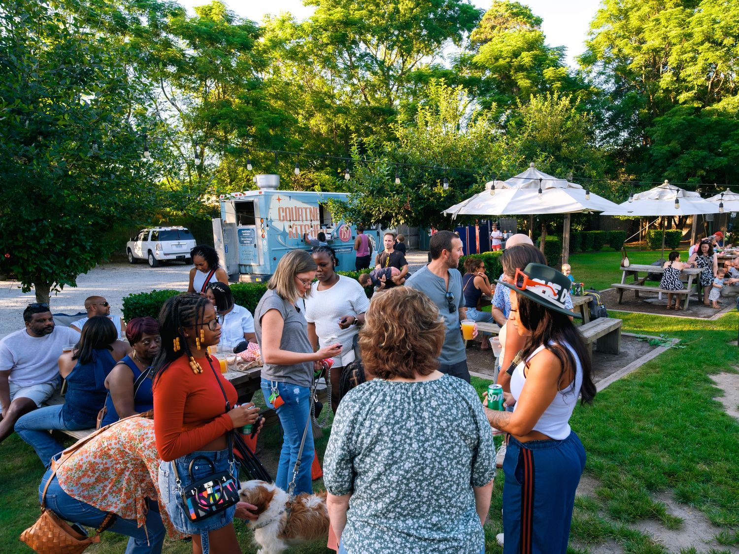 Crowd of people socializing and mingling at an outdoor community gathering in natural surroundings.
