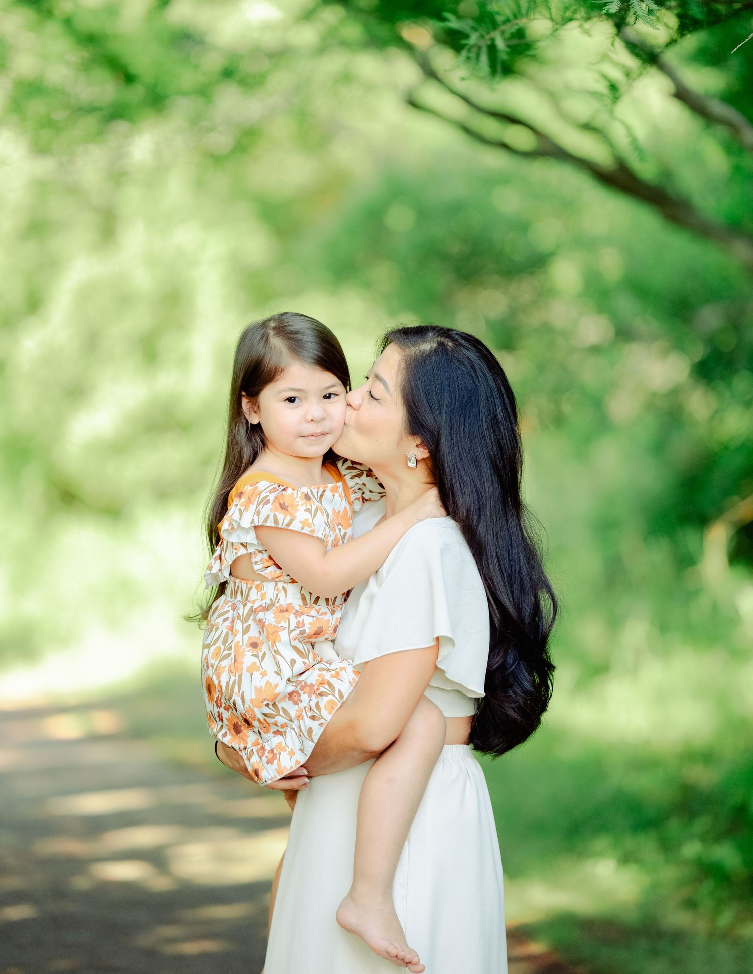 A warm outdoor photoshoot in a lush green park setting showcasing tender family moments on a sunny day.