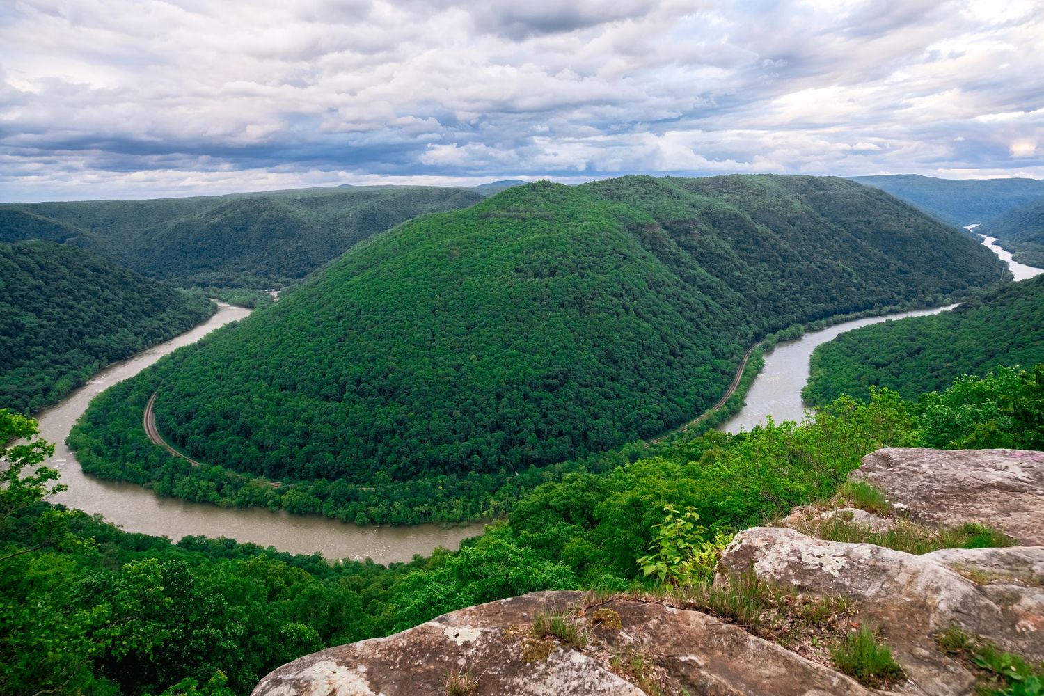 Aerial view of New River Gorge in West Virginia showing dramatic horseshoe bend surrounded by lush green mountains.