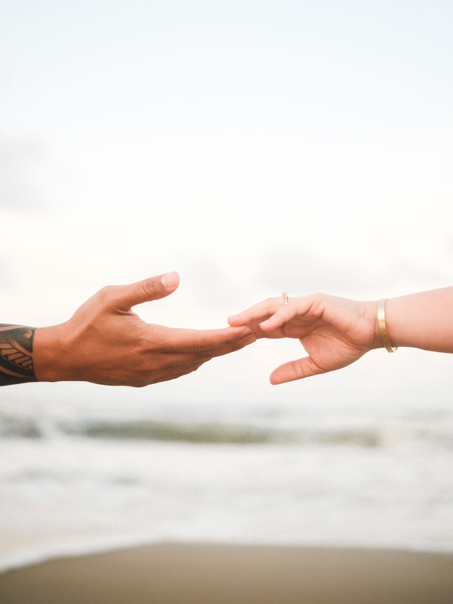 Two hands reaching towards each other against a bright white background.