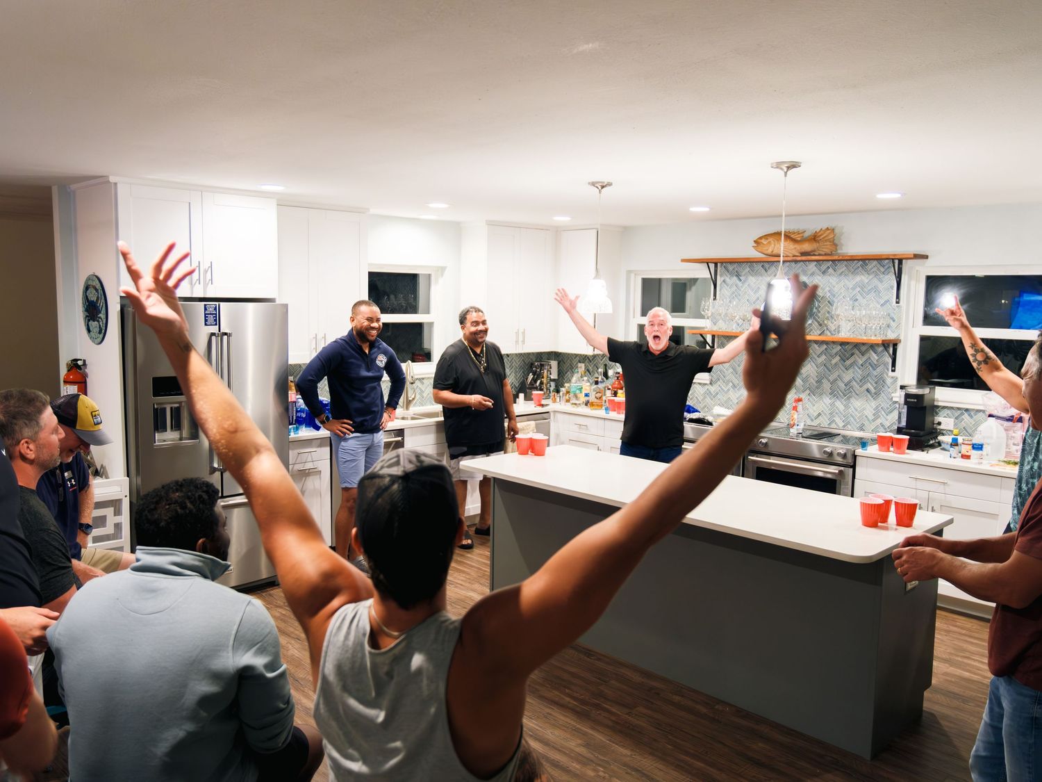 A group stands in a bright office space with raised hands celebrating during a meeting.