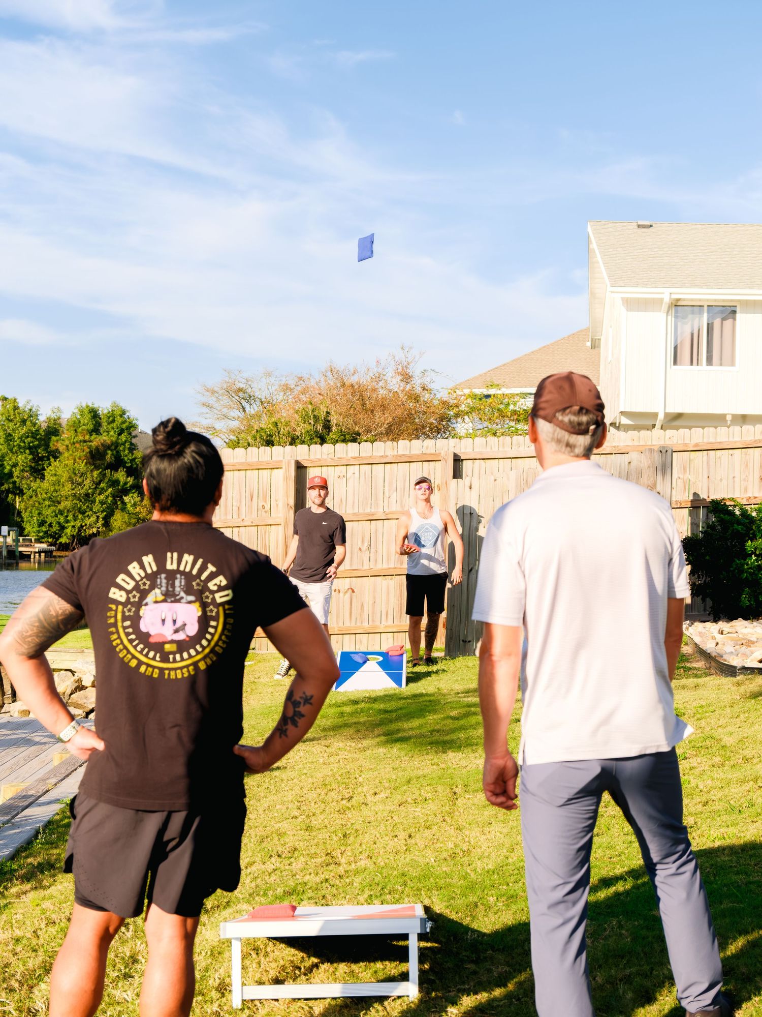 Group of people standing outside by a fence looking at something off in the distance on a sunny day.