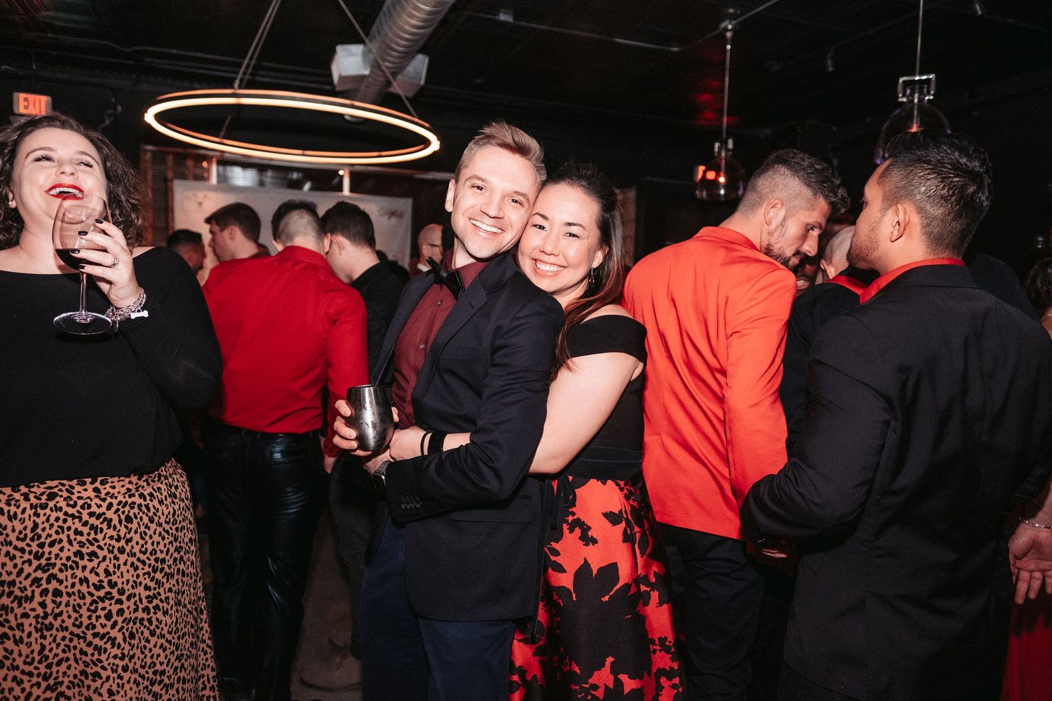 People dancing and socializing at a dimly lit nightclub or party venue with festive lighting.