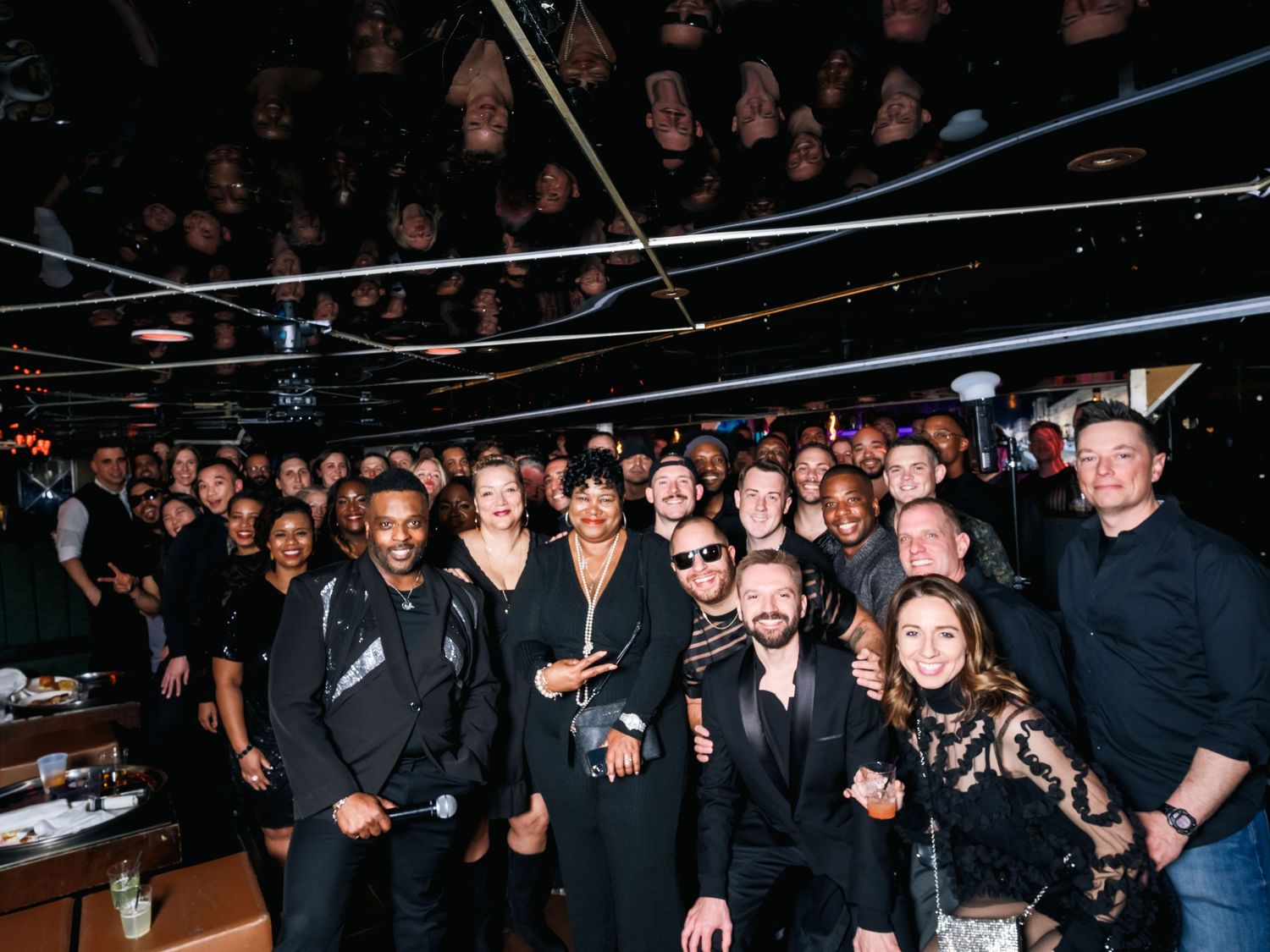 Large group photo of event attendees gathered in a dimly lit venue space.