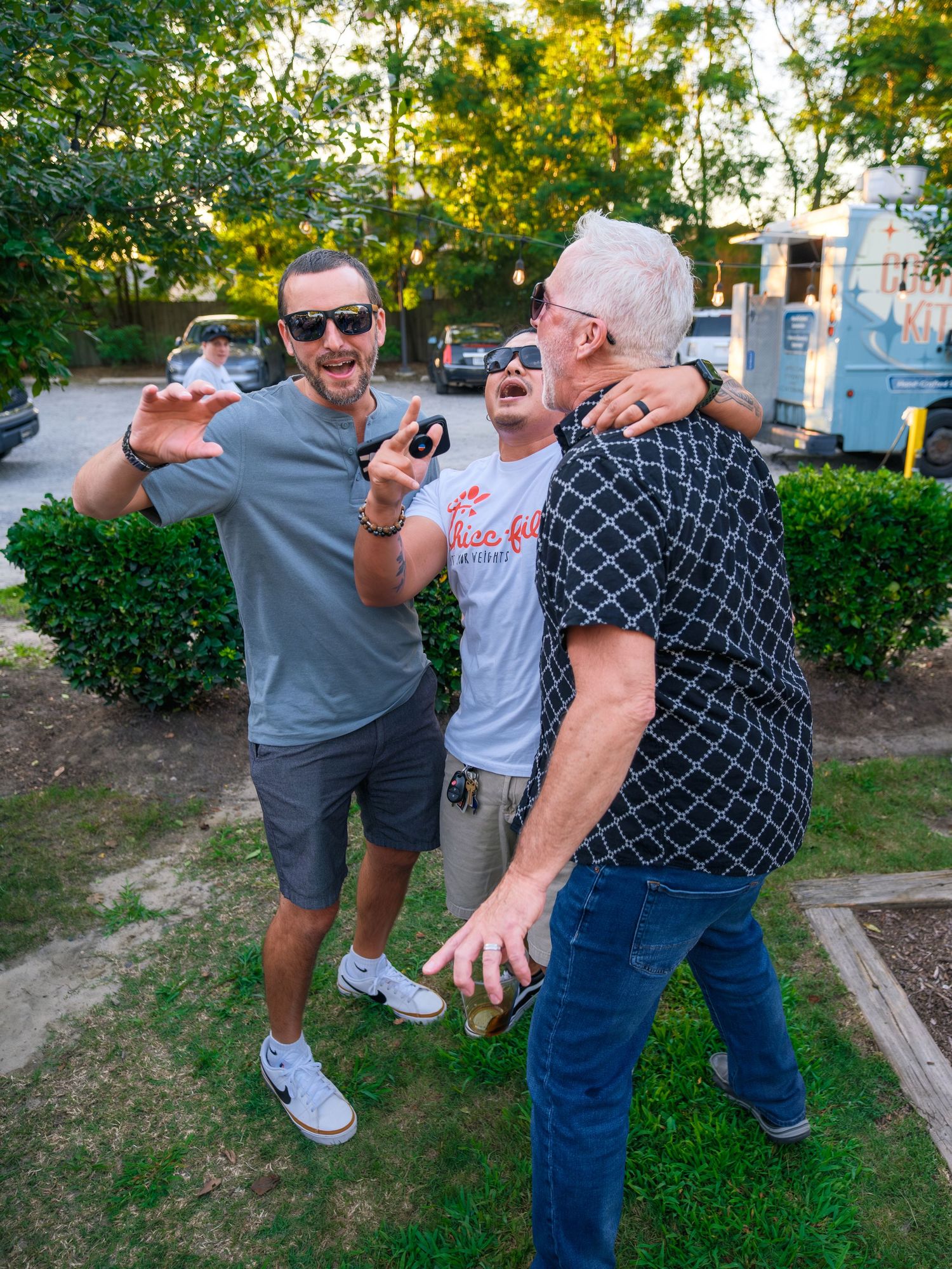 Four sequential photos show people performing exaggerated dance moves outdoors in a garden setting with bushes and trees.