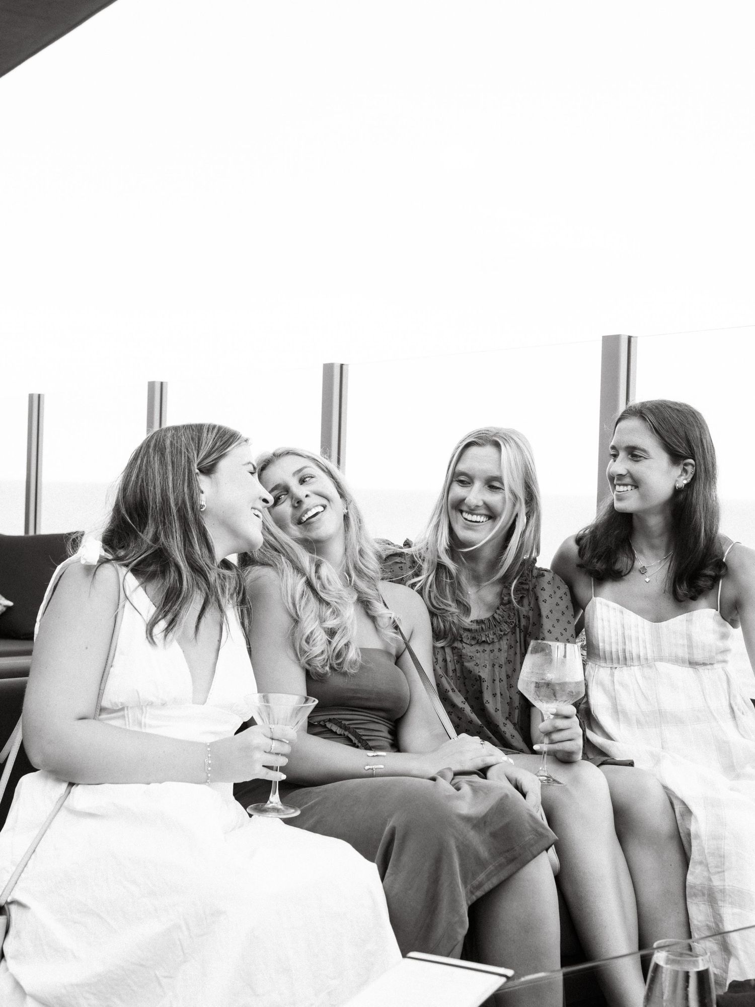 A group of women sitting together and laughing in black and white vintage style photo.