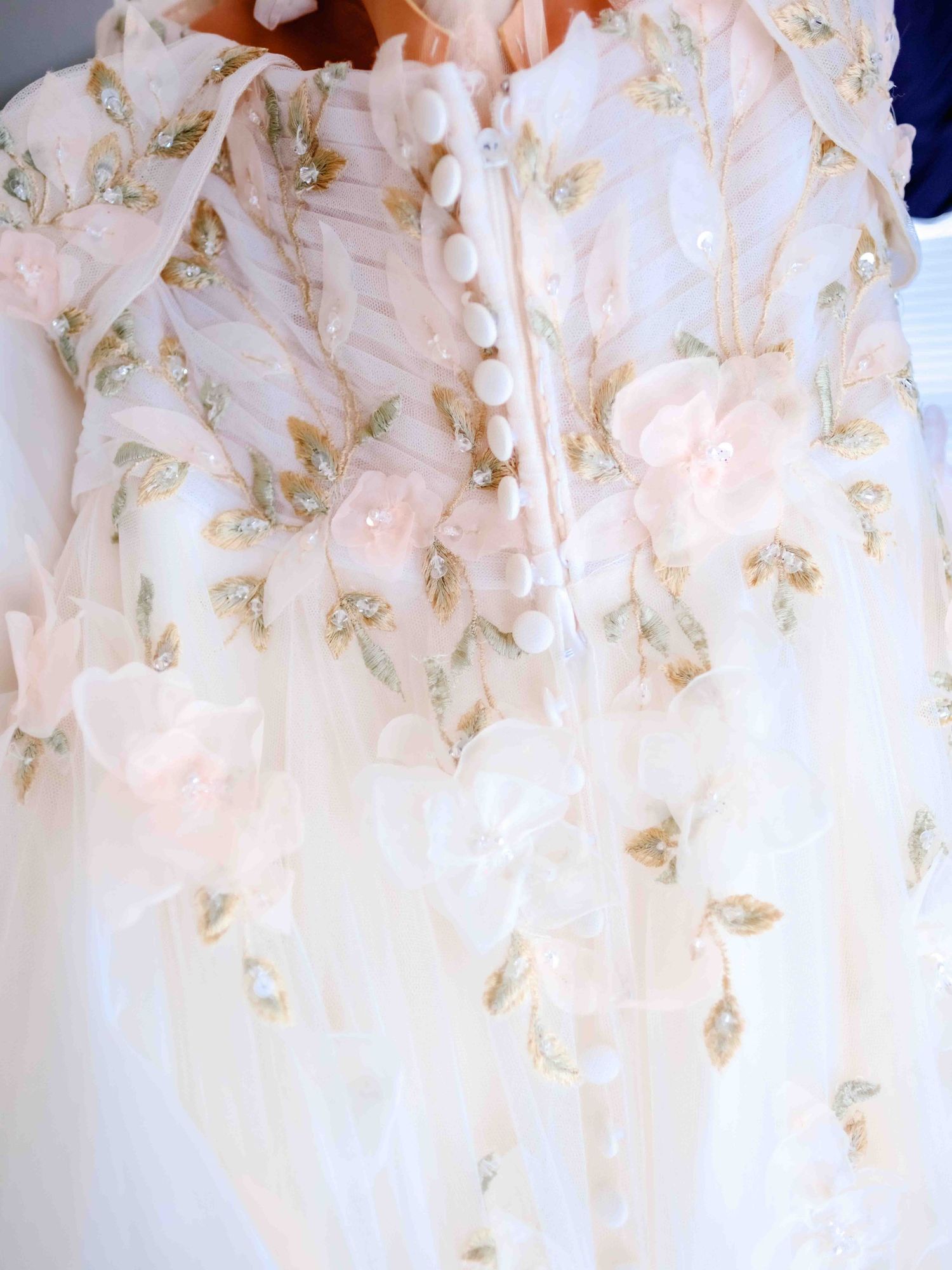 Close up of delicate floral embroidery and beading details on white wedding dress fabric.