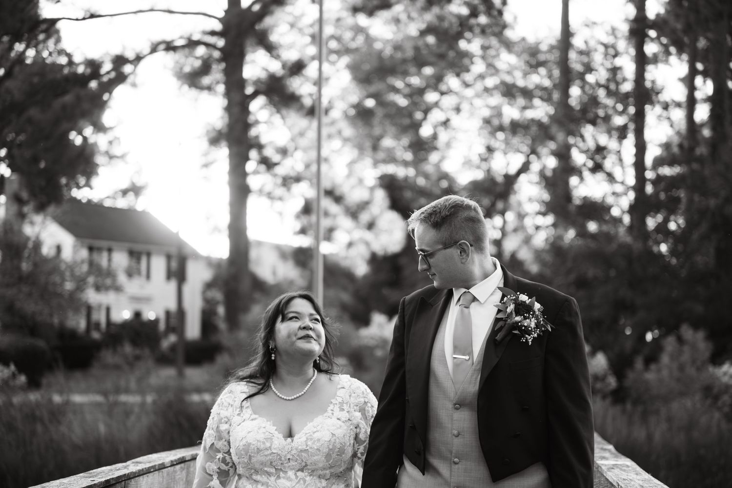 A romantic black and white candid wedding photo of a couple sharing a joyful moment outdoors.