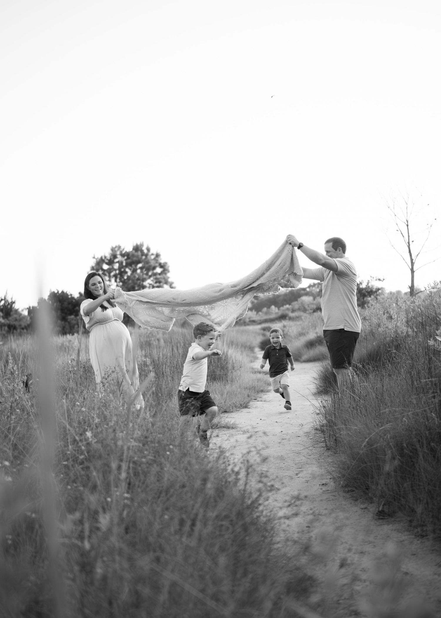 Several figures ascend a sandy hill path lined with desert brush under gray skies.