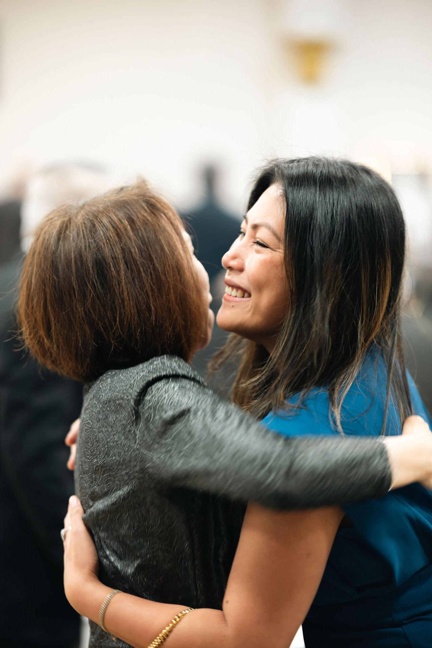 Two people sharing a warm, emotional embrace with one wearing gray and the other in blue.