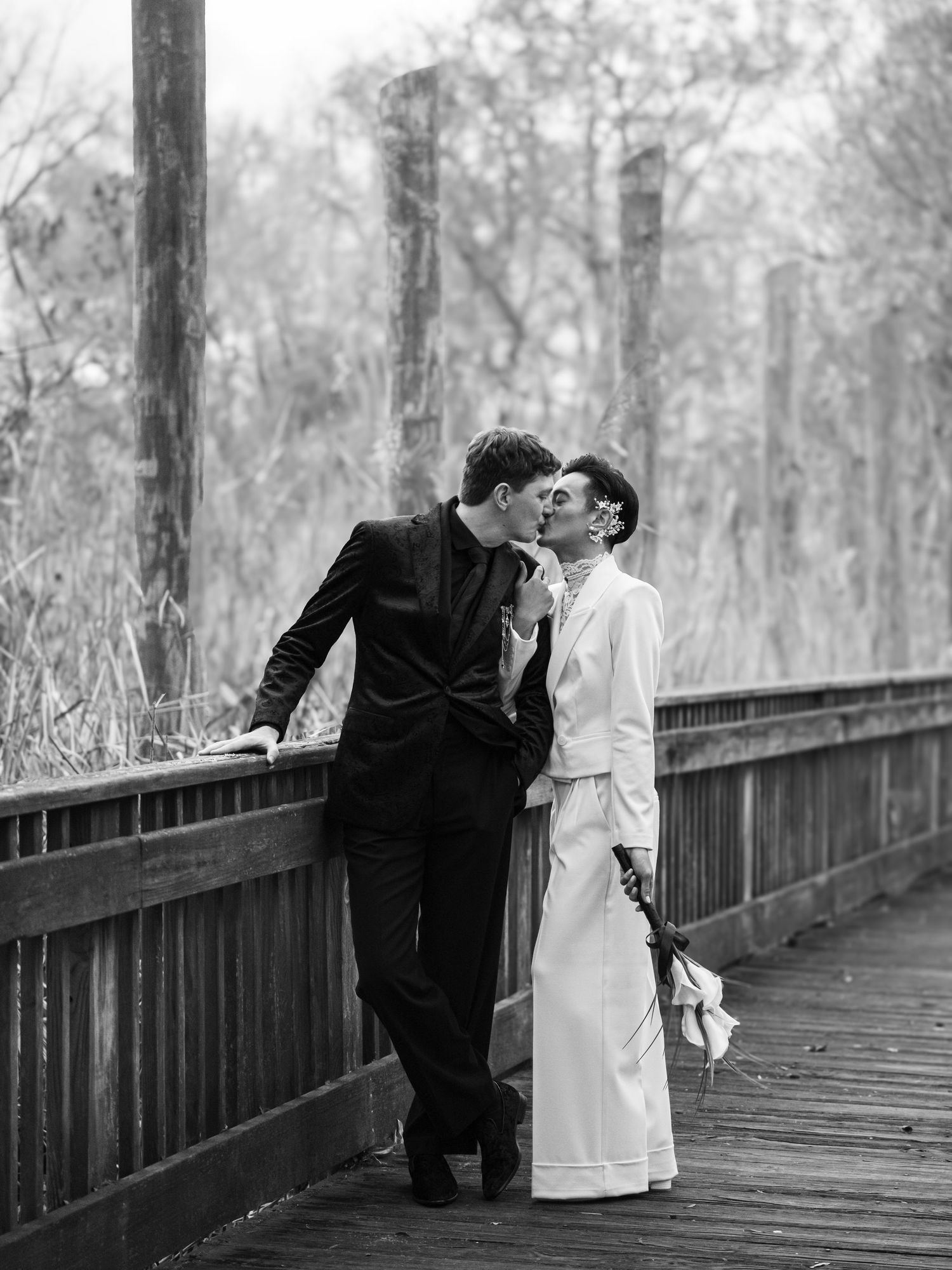 A romantic couple sharing tender moments on a wooden bridge in a misty forest setting.