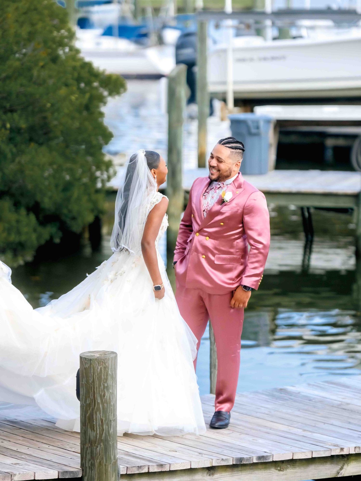 A couple poses together on a wooden dock by the water during their wedding photoshoot.
