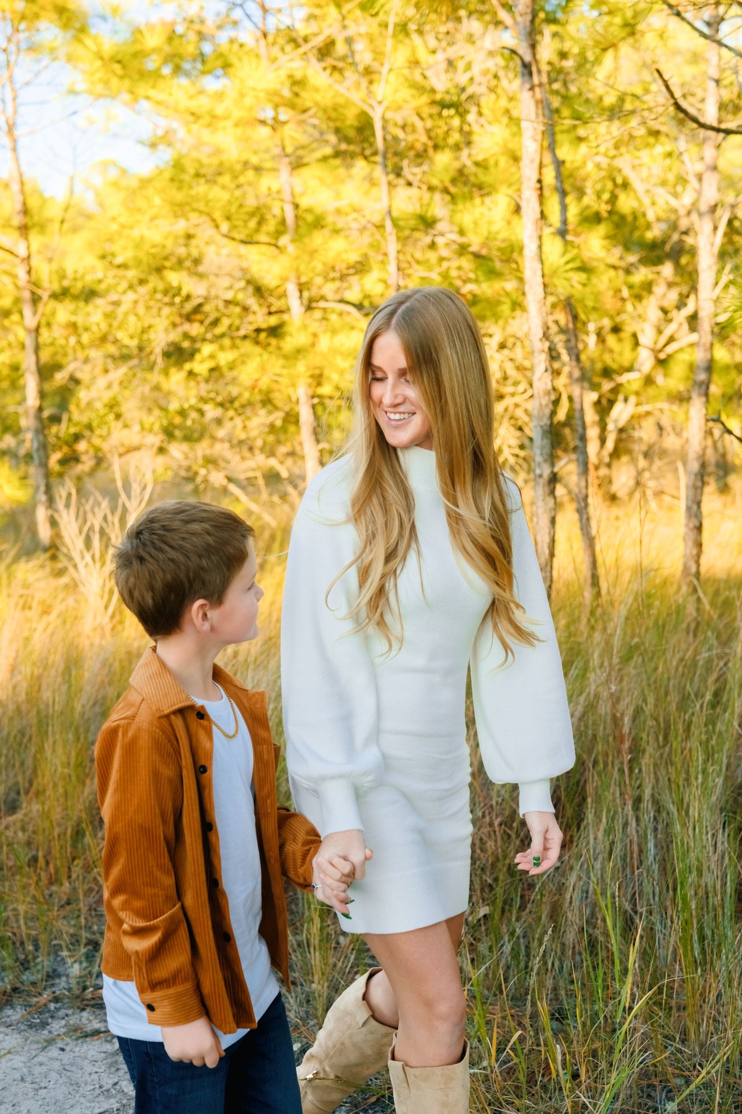 A tender family moment captured in golden sunlight among tall grasses and trees during an outdoor photo session.