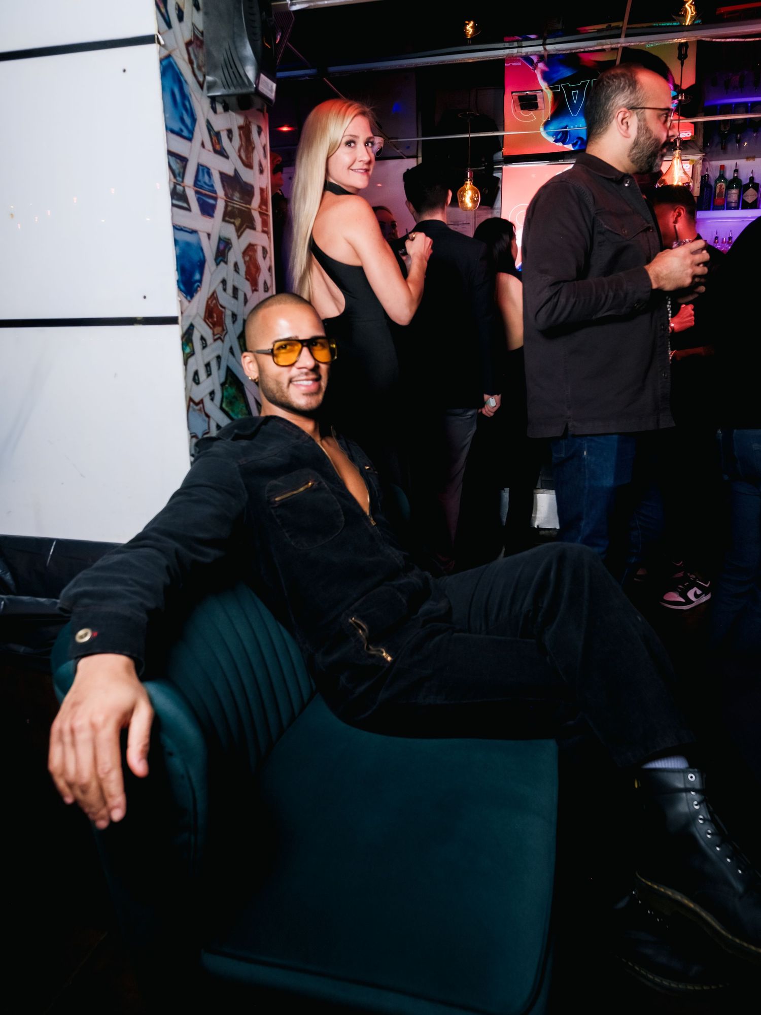 People enjoying themselves at a dimly lit bar or nightclub with atmospheric lighting.