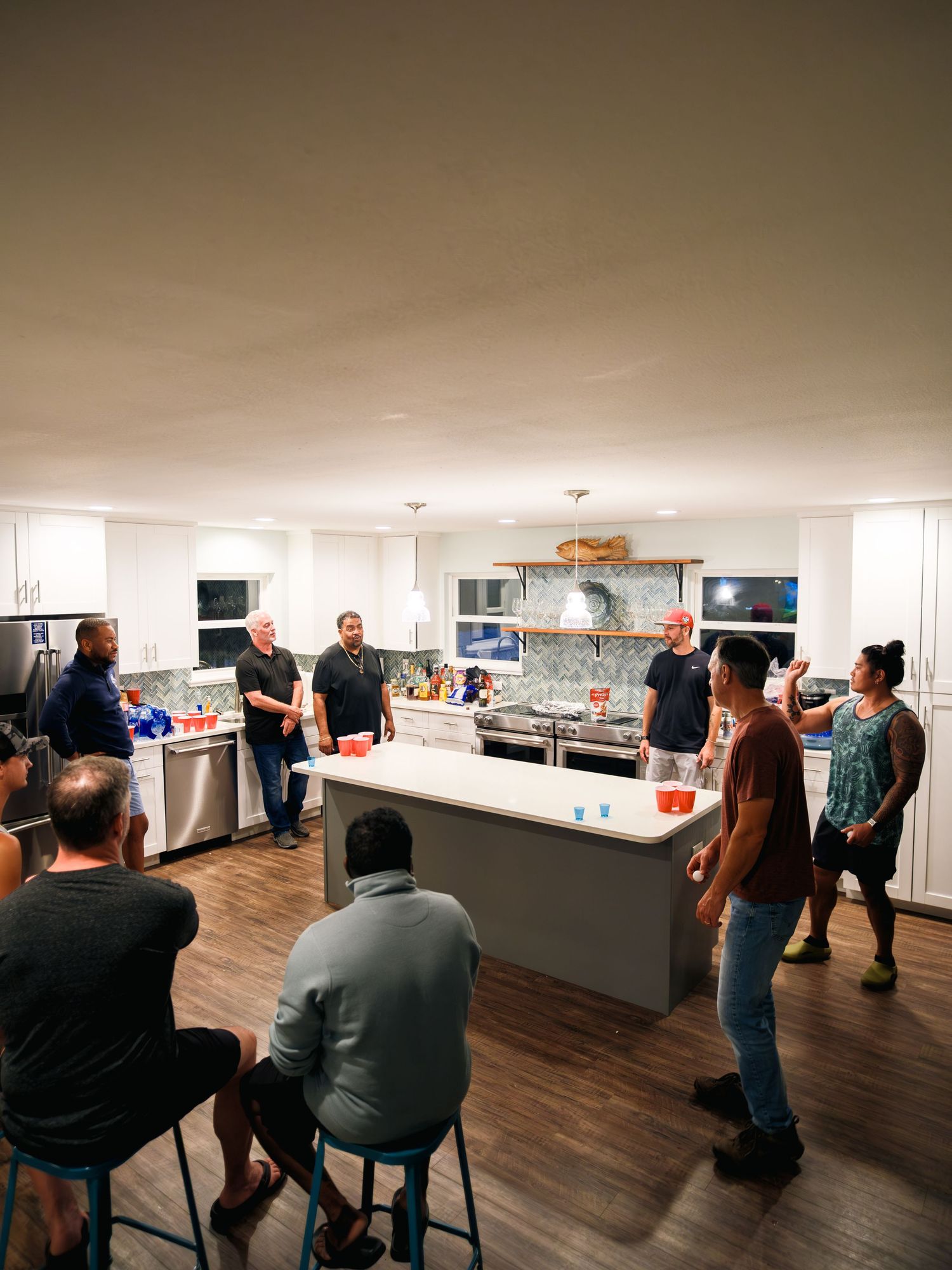 People gather in a modern room with white walls and hardwood floors for a social or networking event.