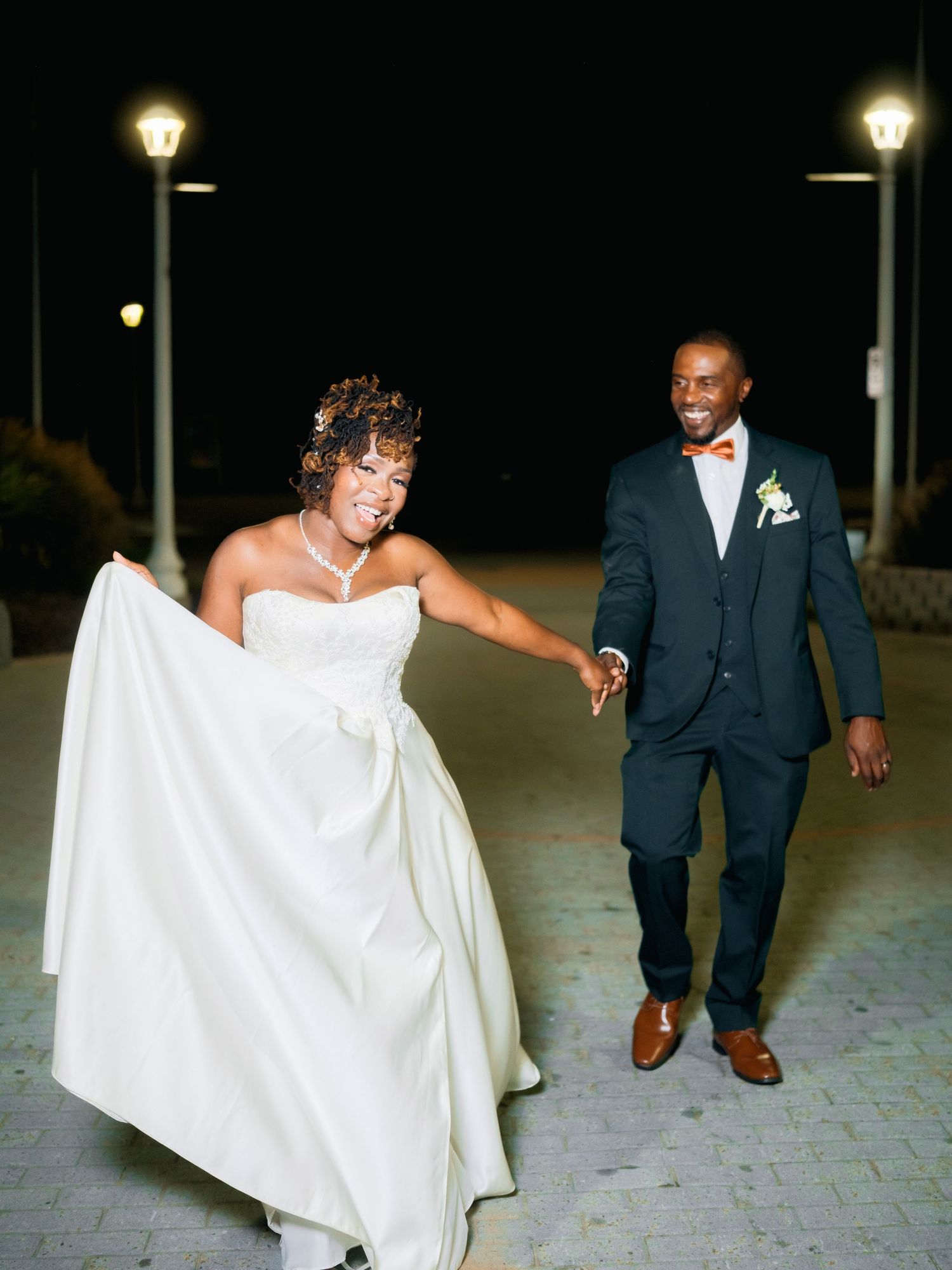 A nighttime wedding photo series showing a couple walking along an illuminated brick pathway.