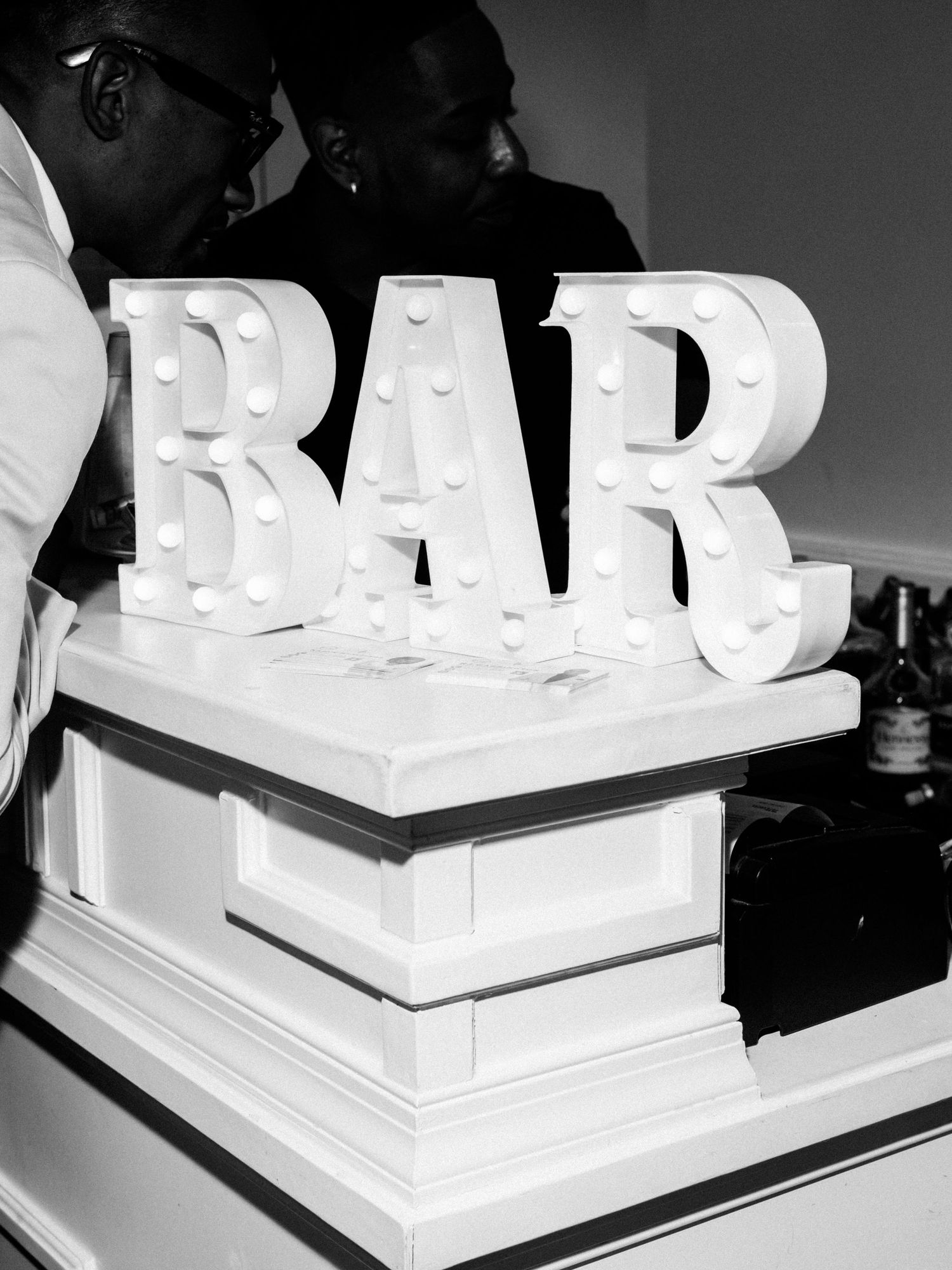 Black and white photo of a tiered white wedding cake with modern geometric DAD text decoration on top.