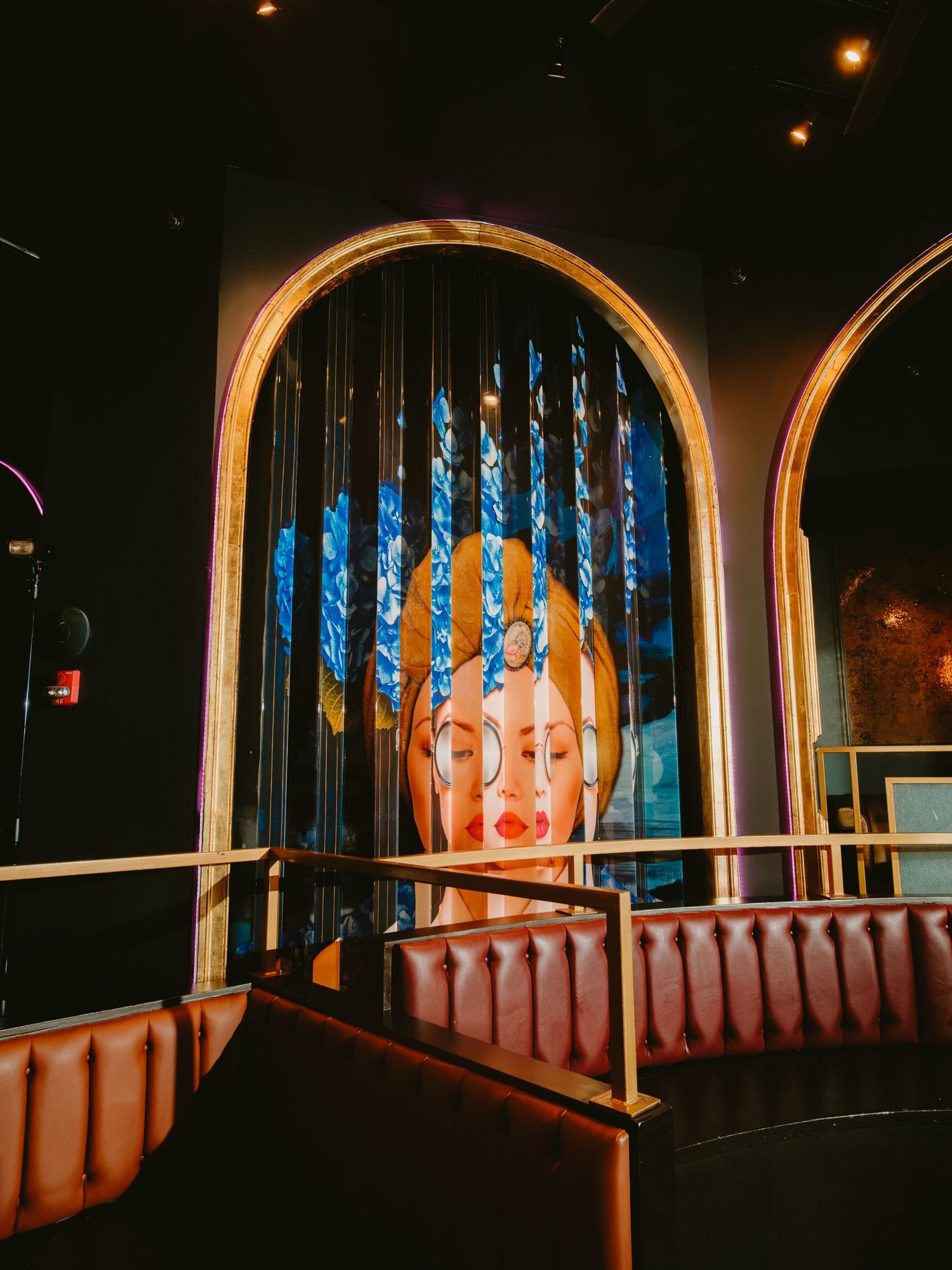 Neon artwork display featuring illuminated blue lights behind glass in an arched window frame at a nightclub or bar.