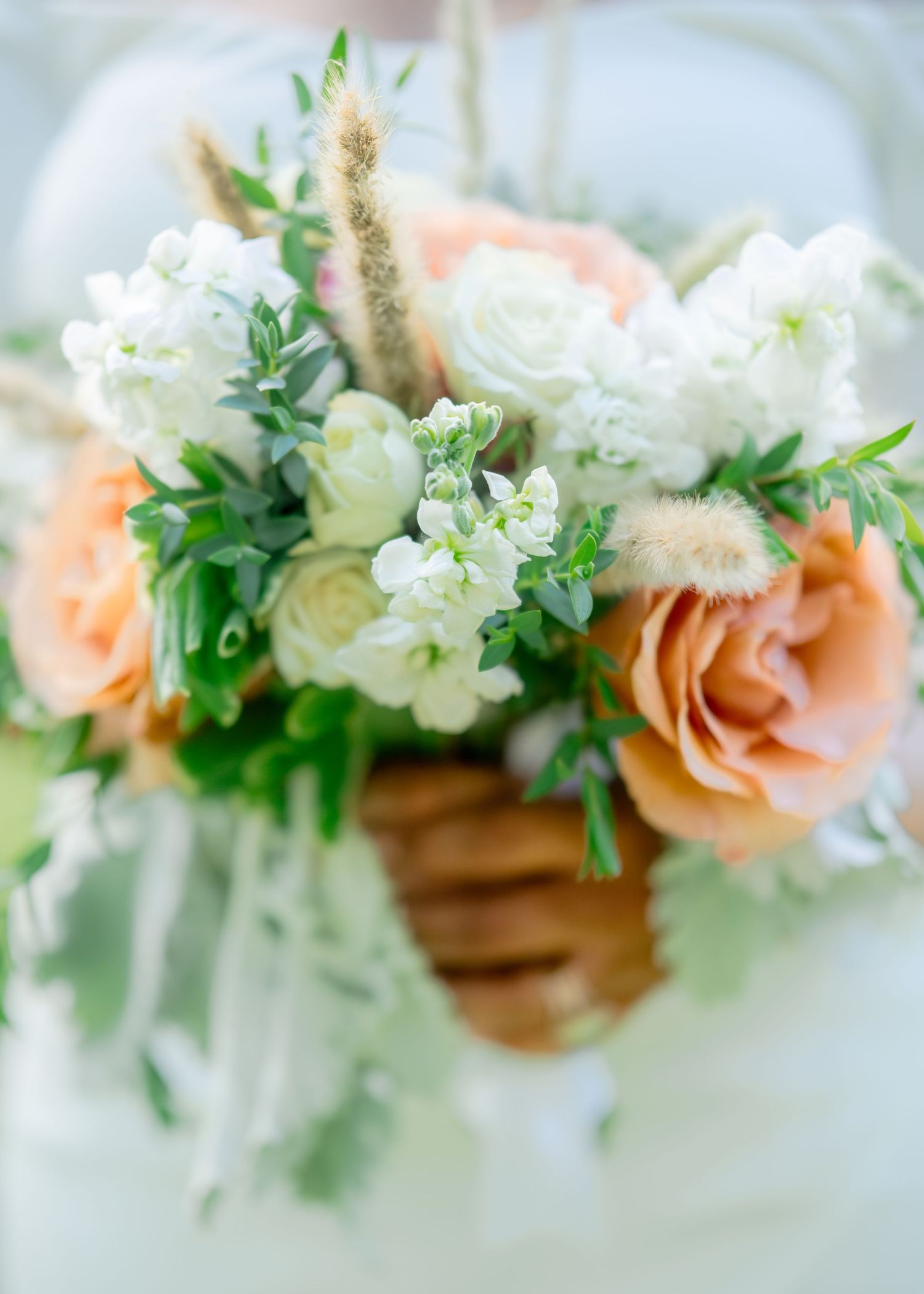 A delicate floral crown with white flowers, peach roses and greenery arranged in an elegant arc for a whimsical look.