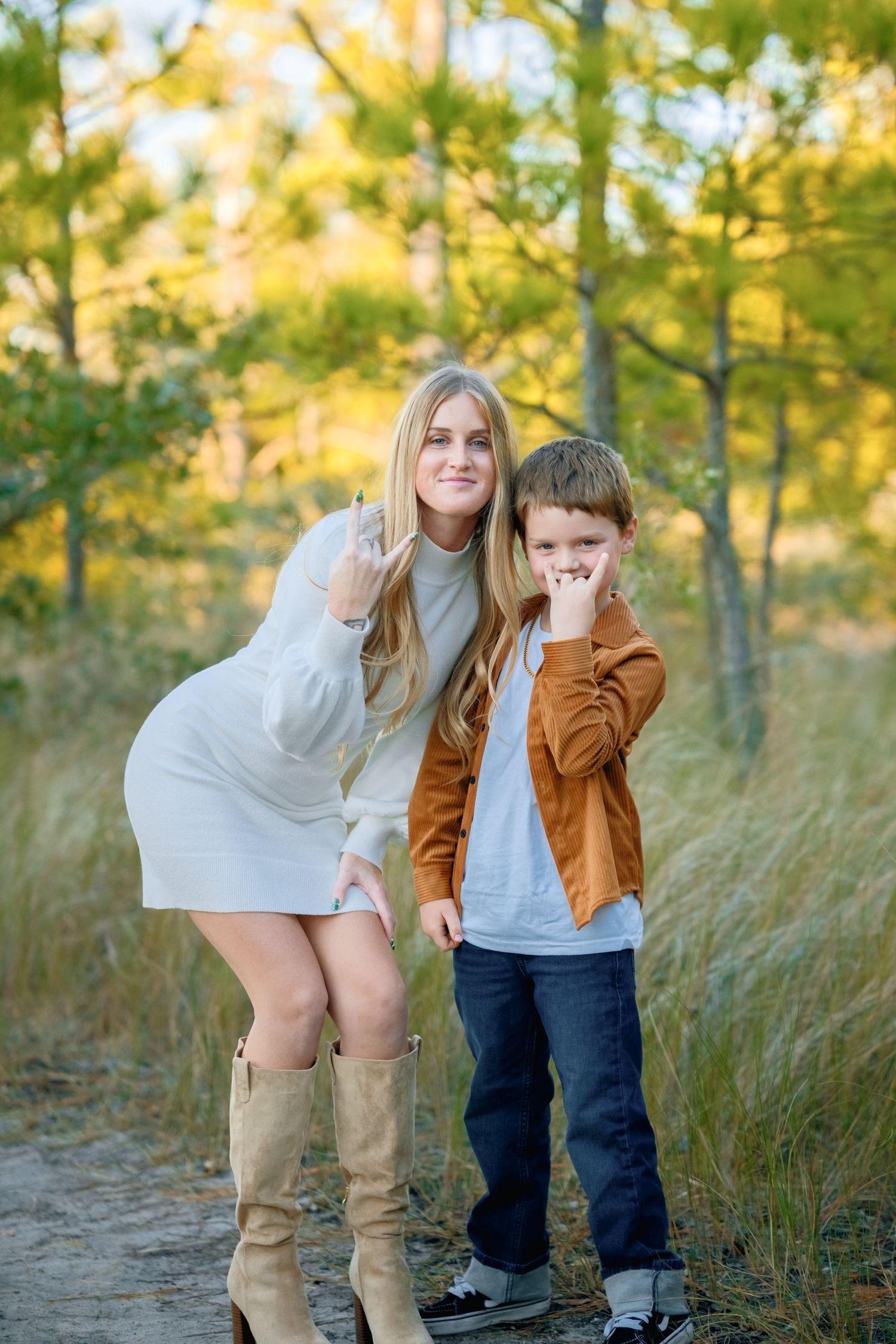 A playful outdoor photoshoot in a golden forest setting with tall grass and warm autumn lighting.