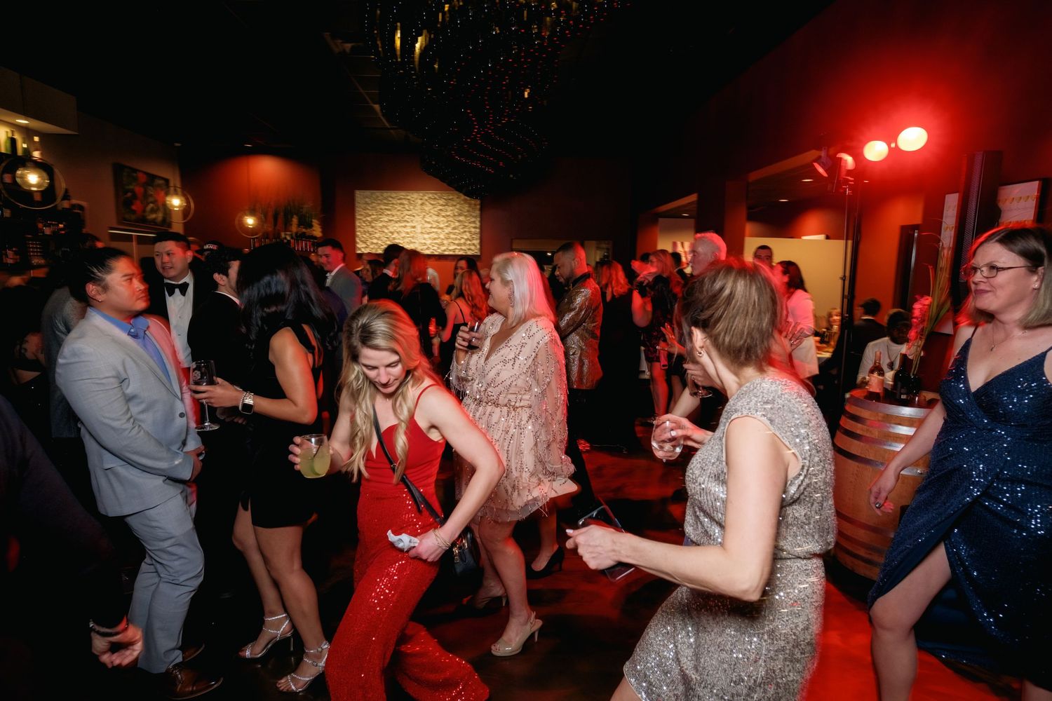 Lively party scene with people dancing under red lighting at a nighttime celebration.