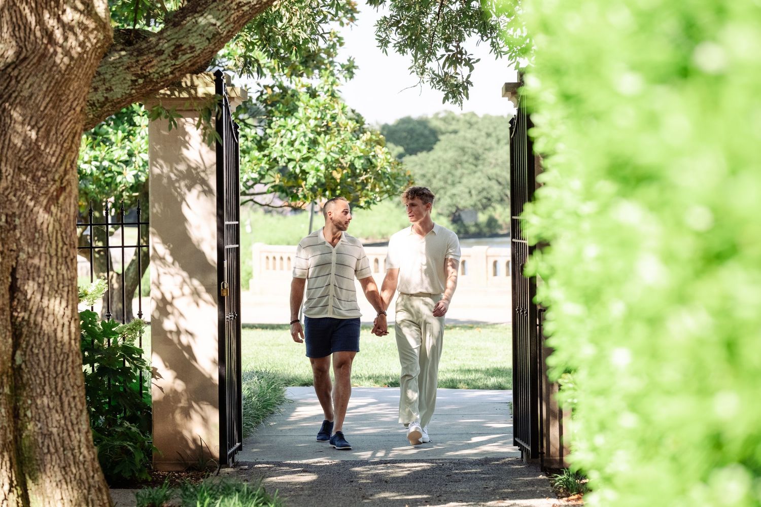 Two people walking together on a garden pathway on a sunny day with lush greenery surrounding them.