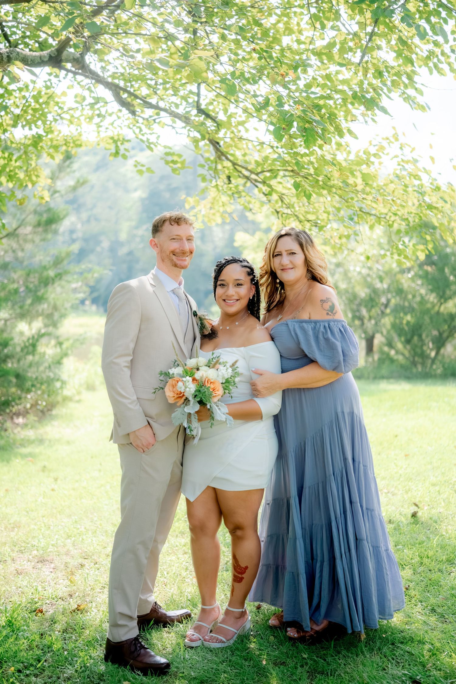 Outdoor wedding photo series showing a couple and attendant laughing together in a sun-dappled garden setting.