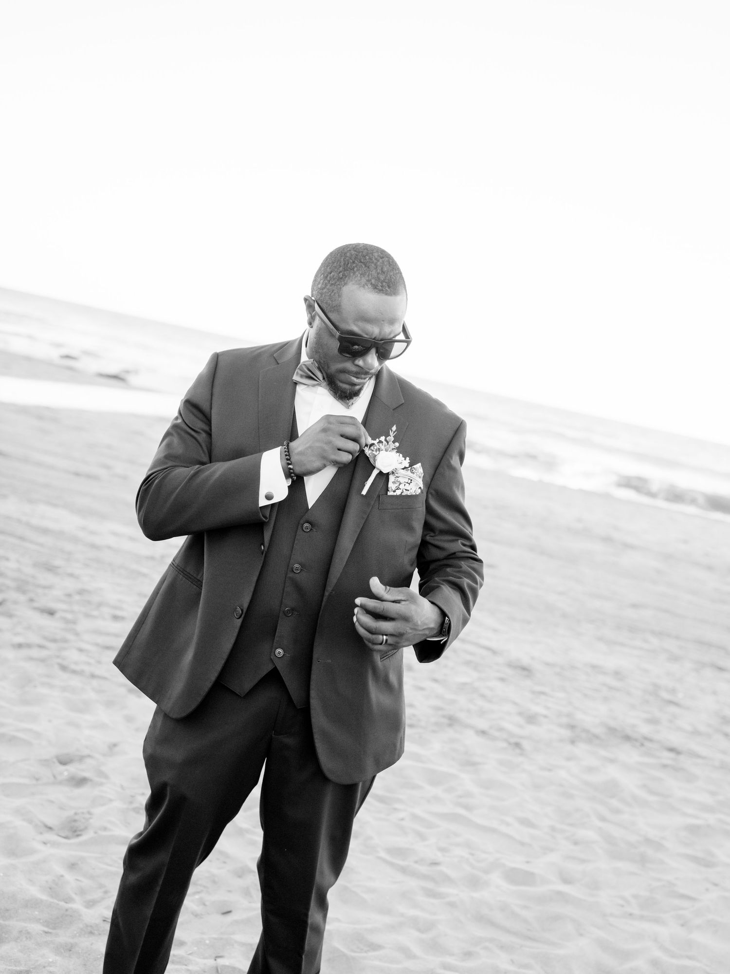 A sequence of playful poses on the beach showing a person in a dark suit bending down.