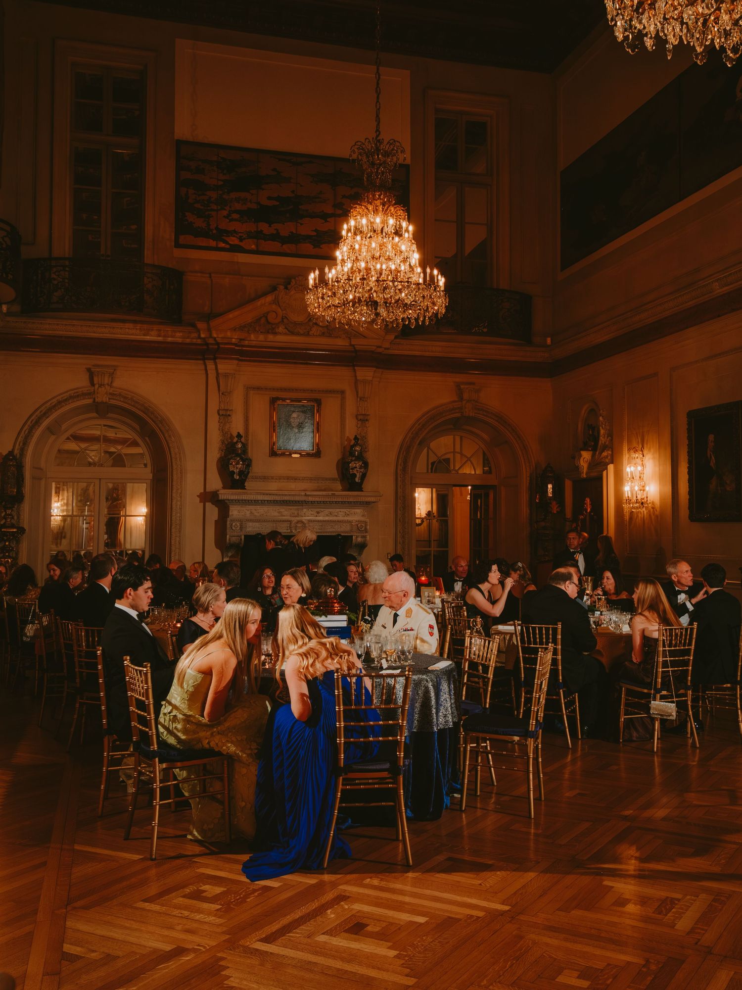Elegant formal dinner reception in a grand ballroom with crystal chandelier and parquet floors.
