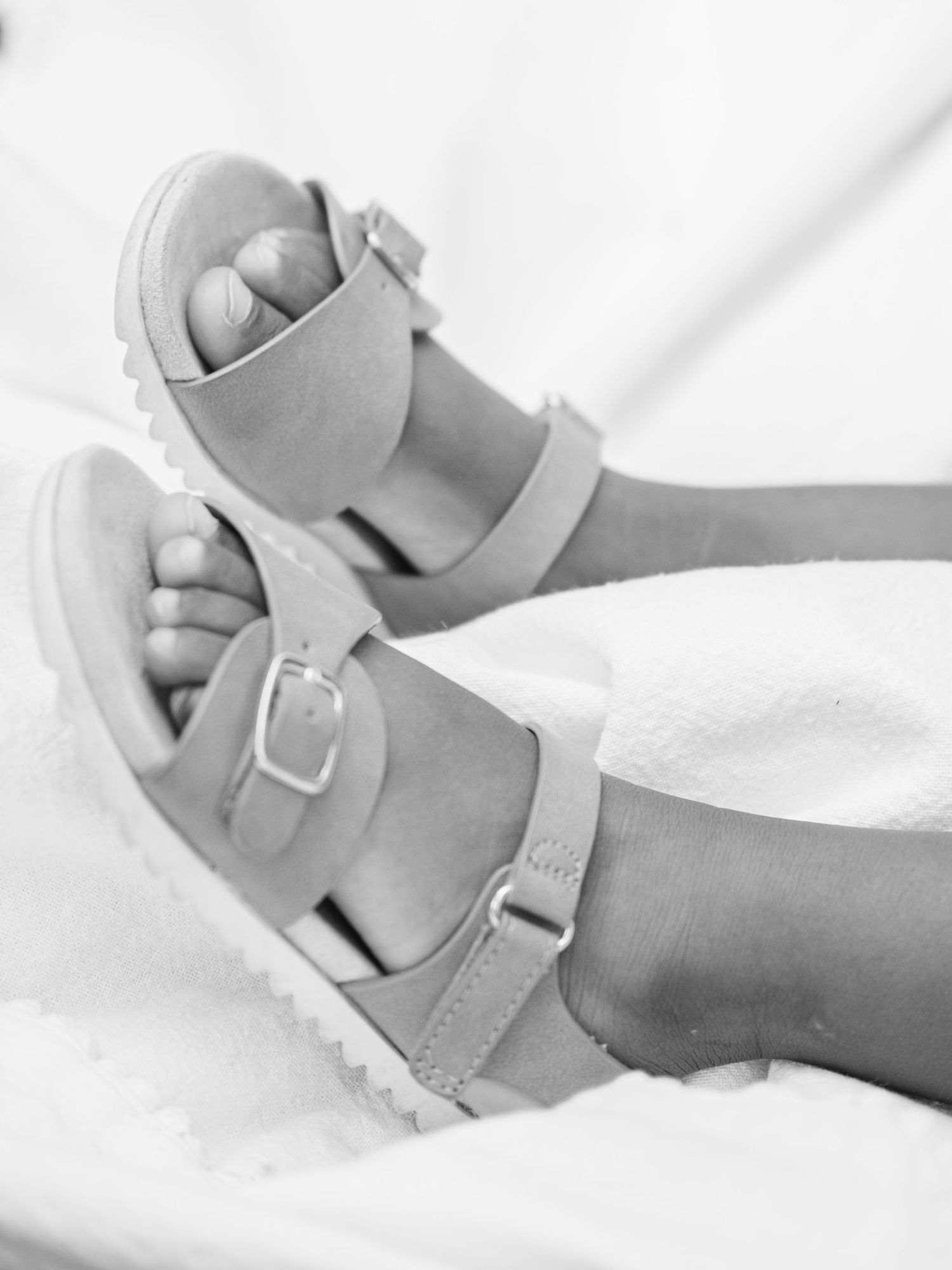 White platform sandals with buckle straps shown against a bright white background in a minimalist style.