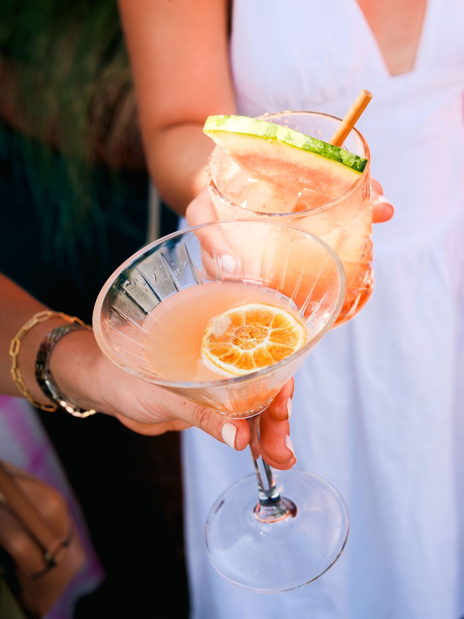 Pink grapefruit cocktails with citrus garnish served in martini glasses held at different angles.