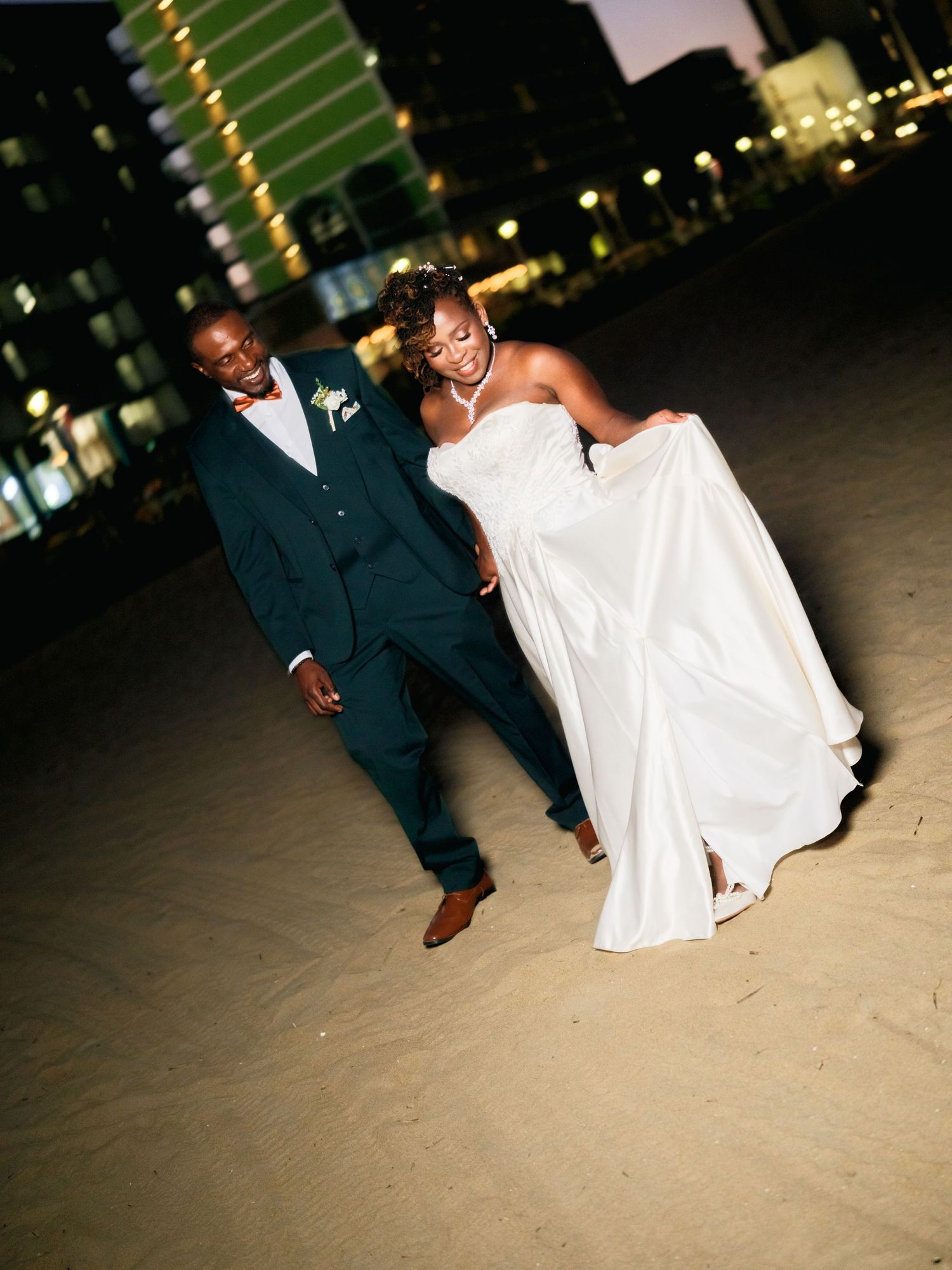 Wedding couple's feet and dress details captured during evening reception with city lights.