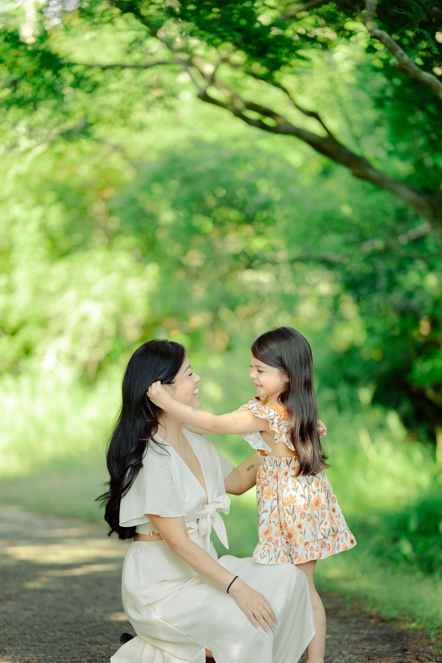 Parent and child share a tender moment together on a wooded path surrounded by lush green foliage.