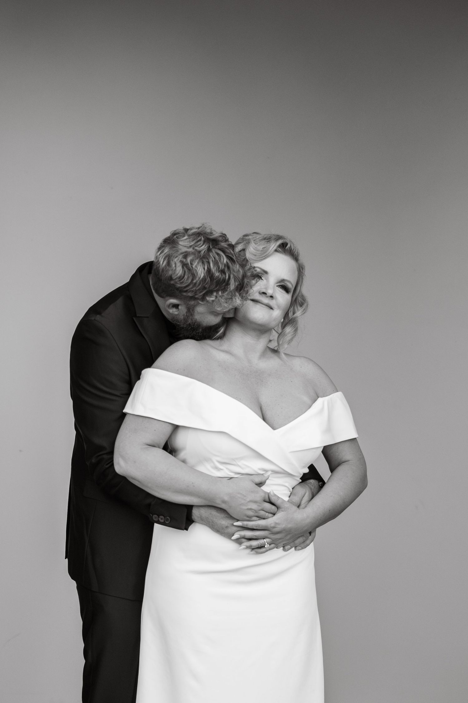 A romantic black and white portrait of a couple in formal attire sharing an intimate moment.