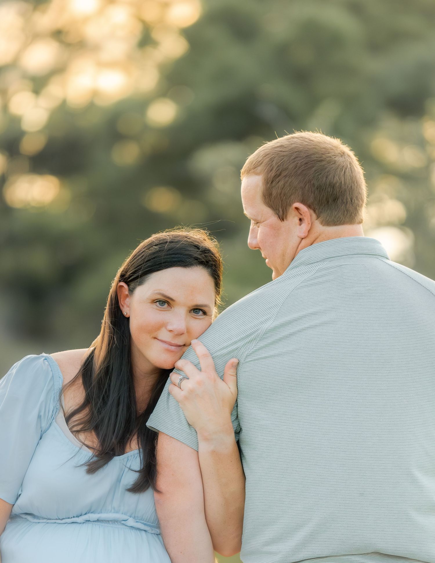 Happy couple embraces in a sun-drenched outdoor setting during a romantic photoshoot.