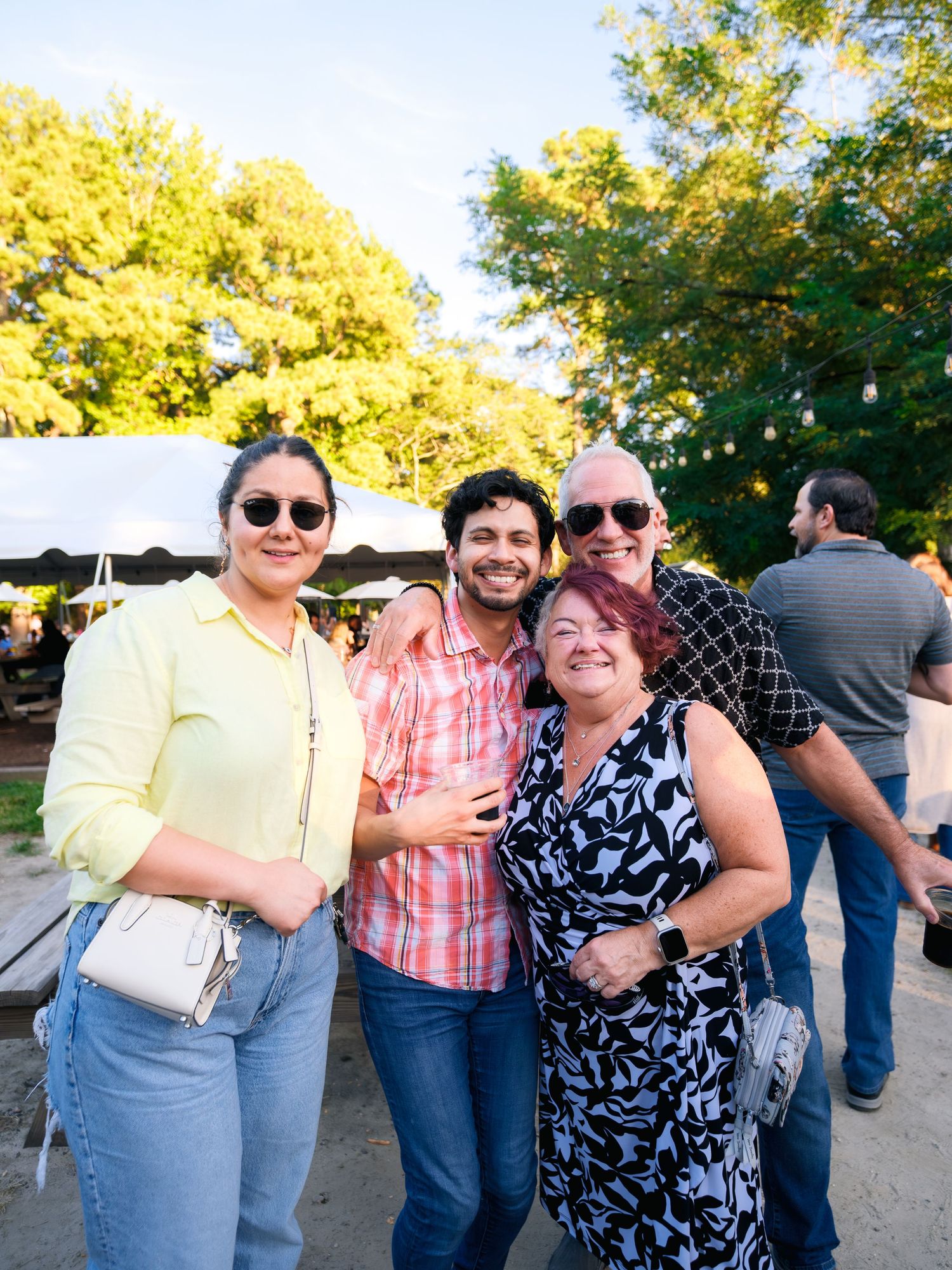A cheerful group of friends enjoying outdoor festivities on a sunny day during a community gathering.