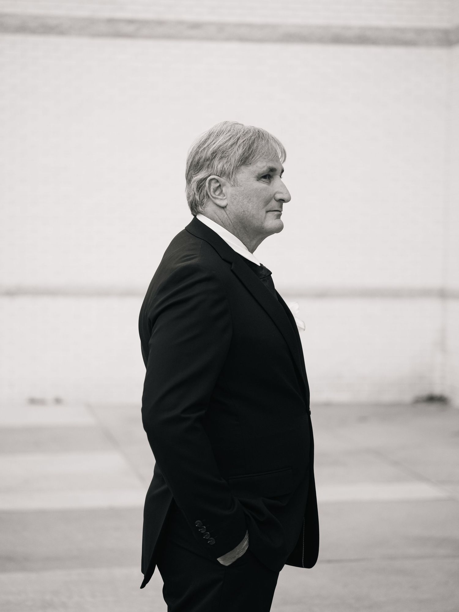 Black and white profile portrait of a gentleman in a dark suit jacket looking into the distance.