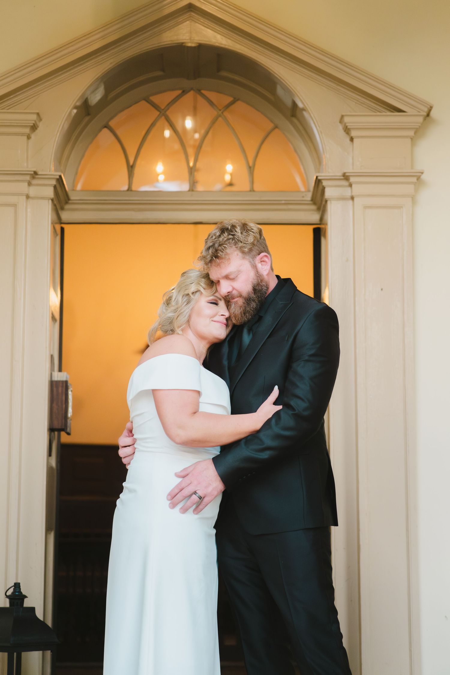 Romantic couple shares tender moments in a grand arched doorway during their first look wedding sequence.