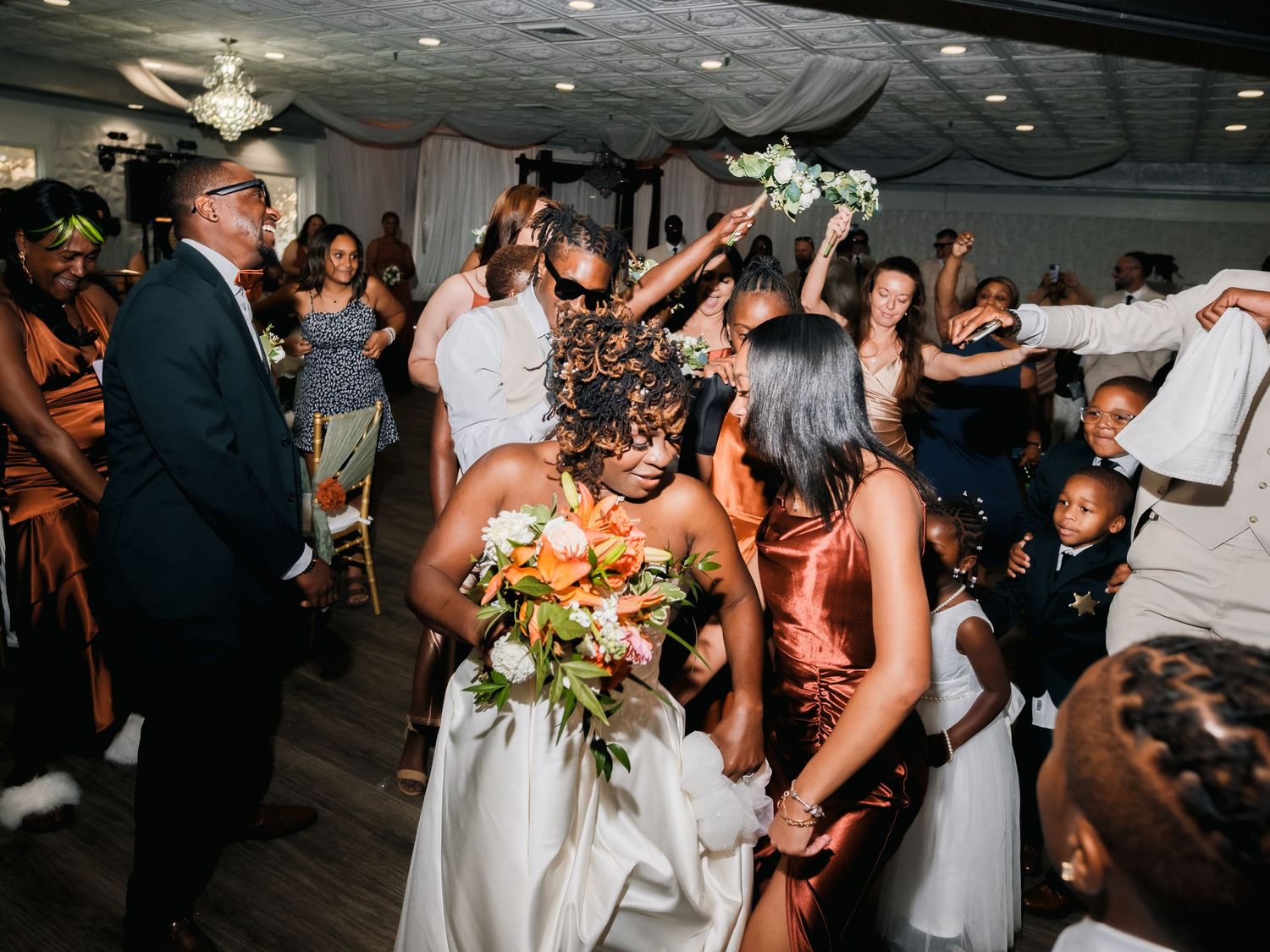 Wedding guests dance and celebrate joyfully on the dance floor during a lively reception party.