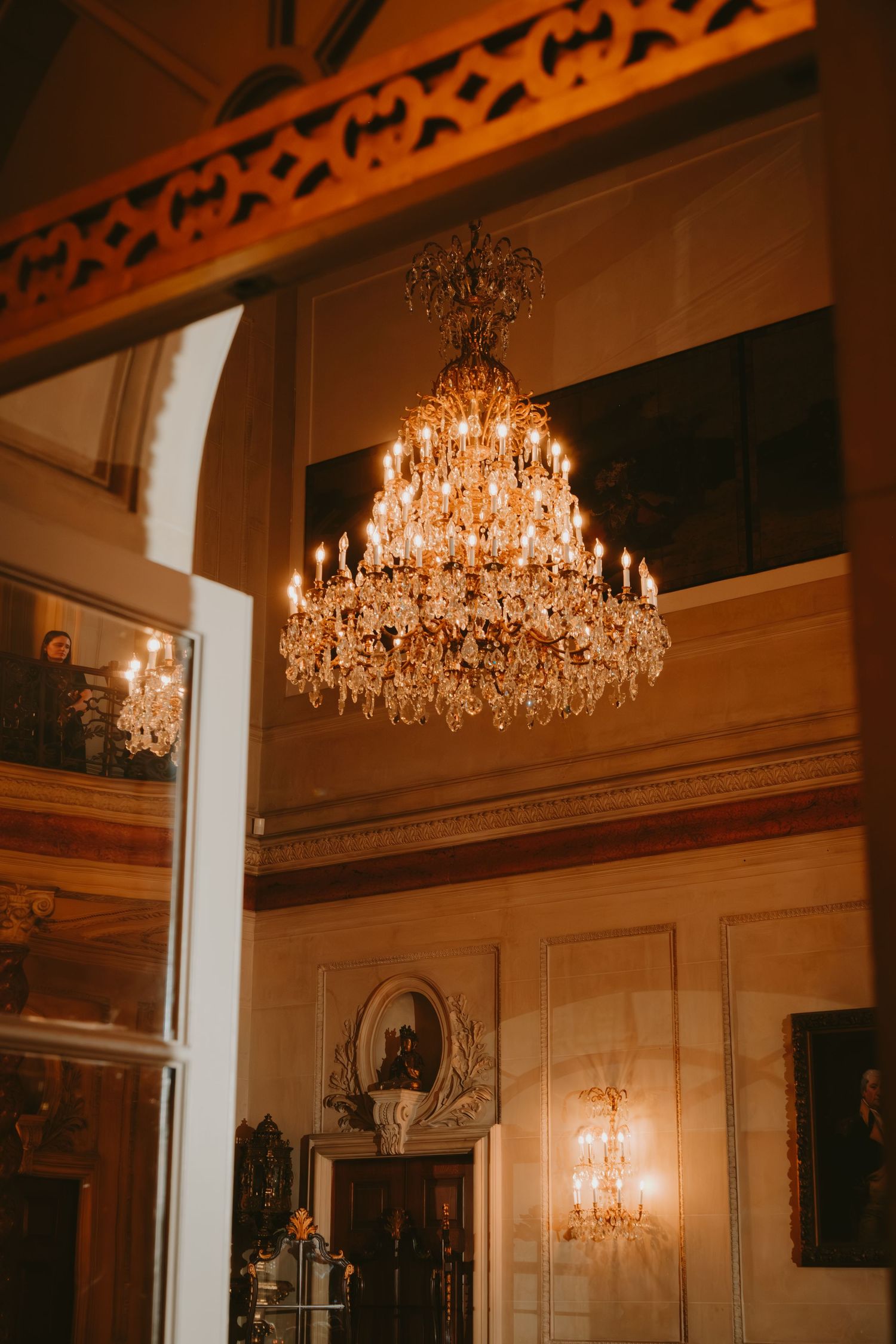 Elegant crystal chandeliers illuminate a grand ballroom with ornate wall details and classic architectural elements.