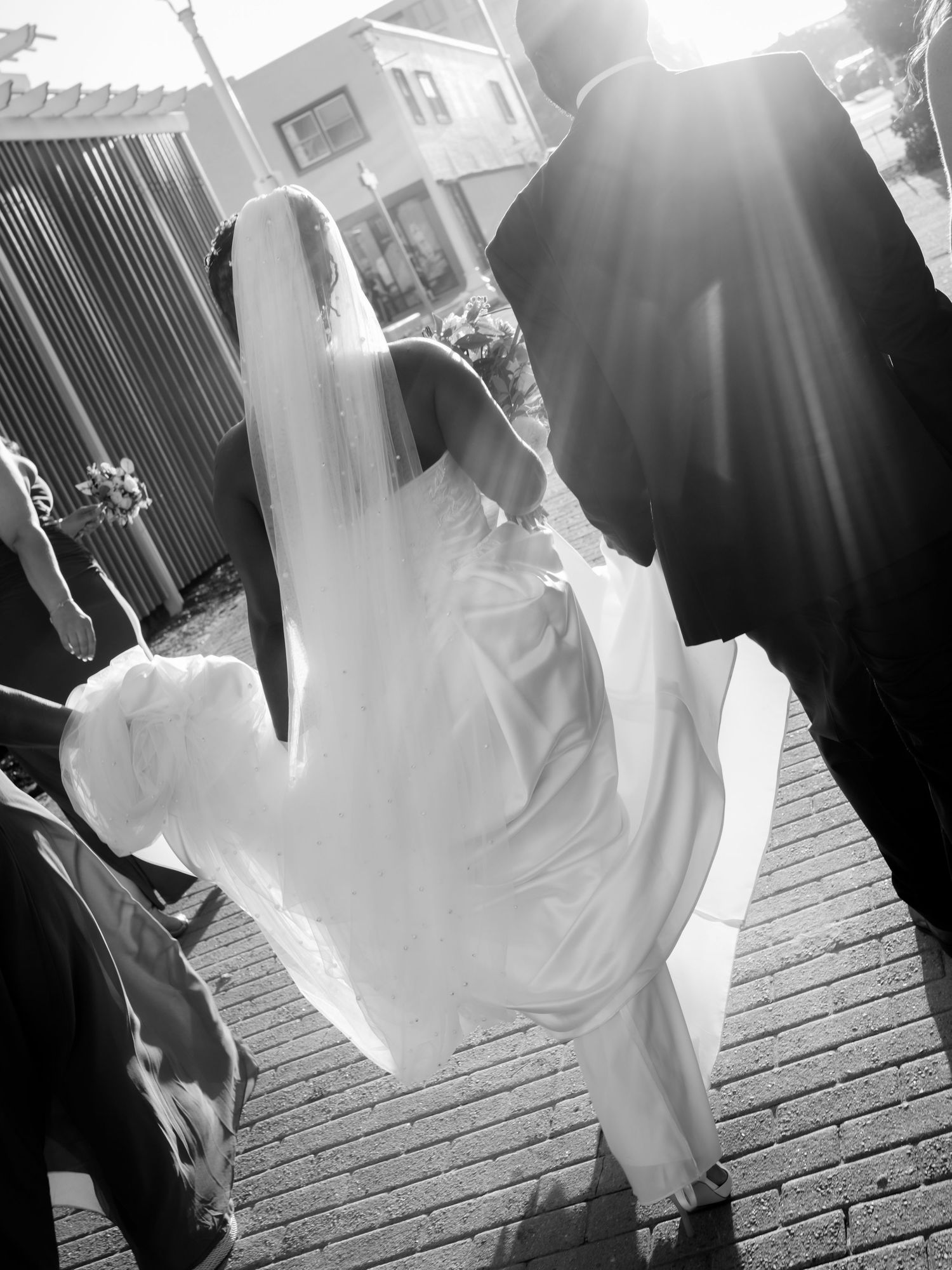 Black and white silhouette of a wedding party walking in dramatic sunlight.