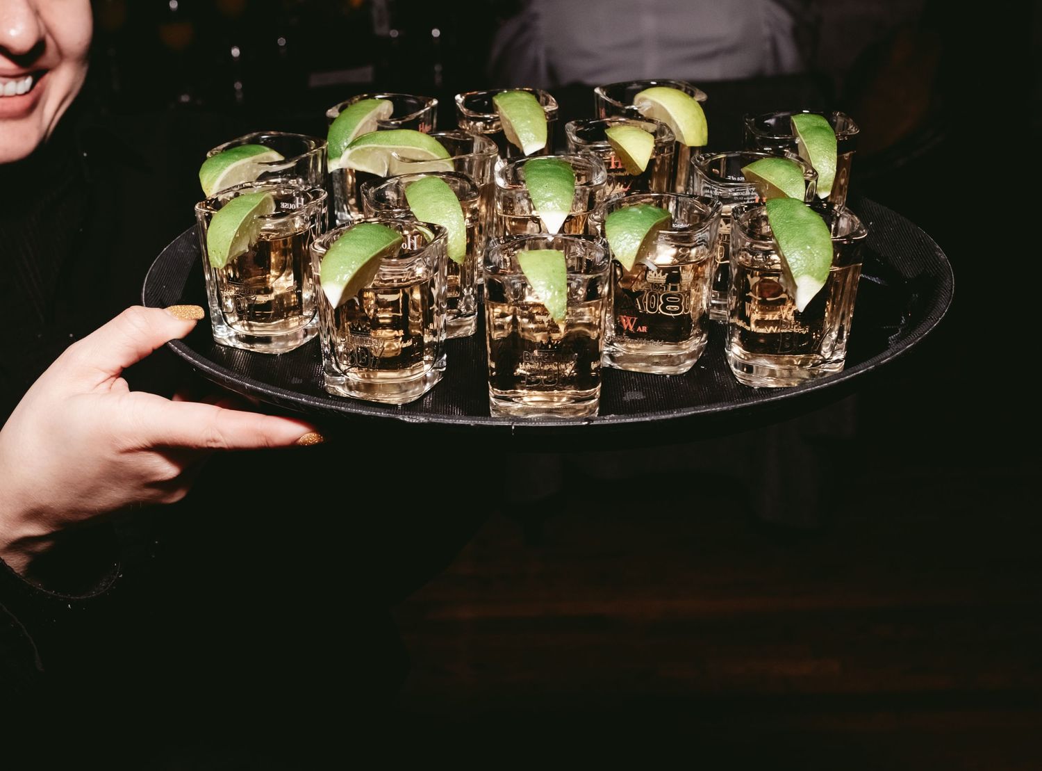 A silver tray of chocolate dessert shooters garnished with lime wedges being served at an elegant event.