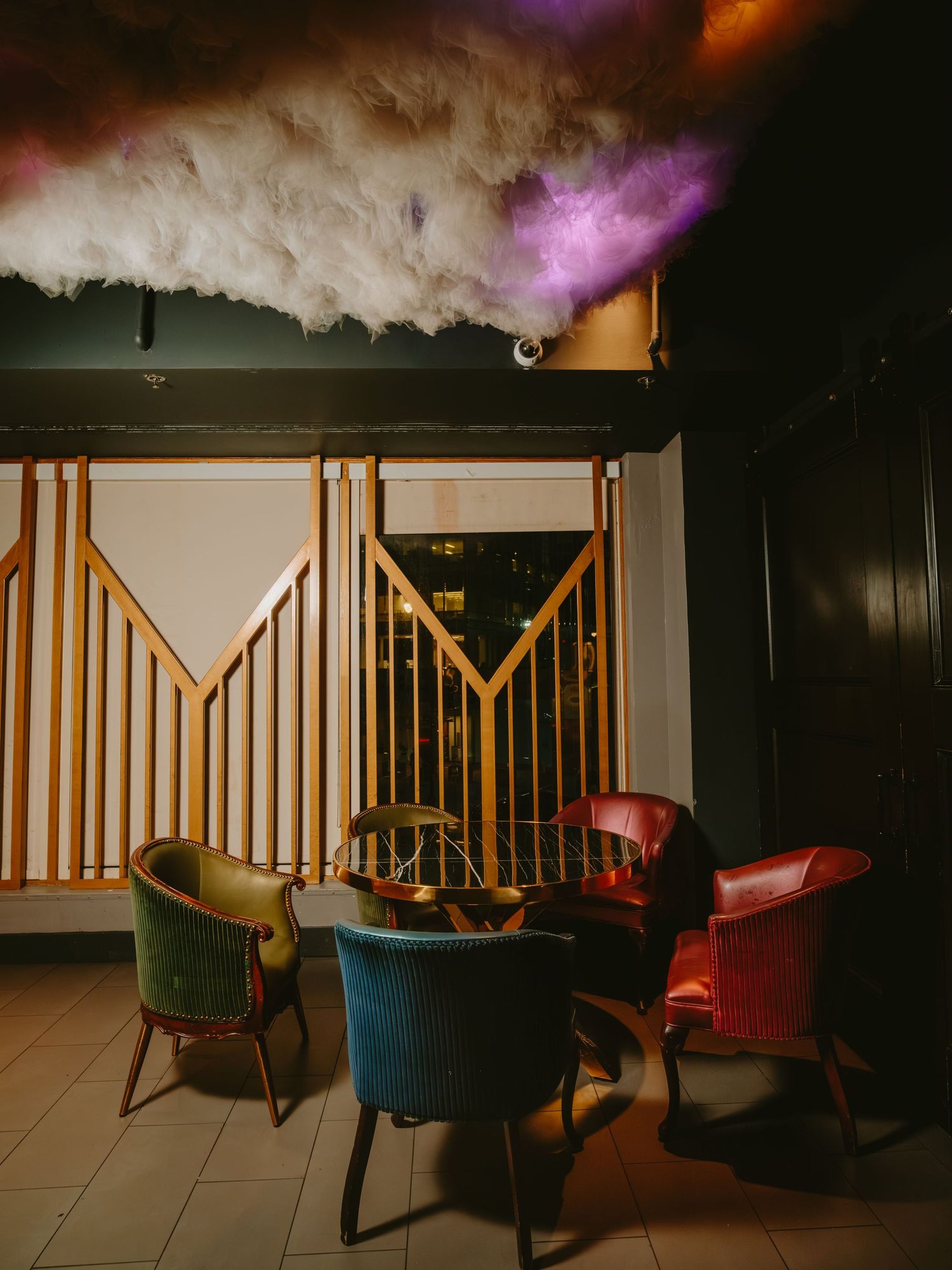 Moody lounge area with colorful chairs and dramatic purple lighting creates an atmospheric nightclub vibe.