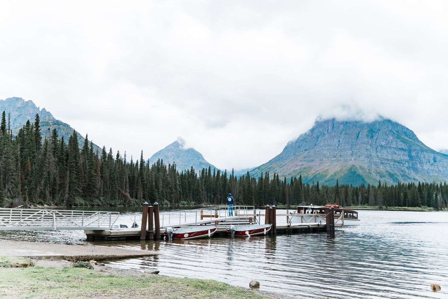 Banff National Park's scenic shoreline features docks extending into turquoise waters with snow-capped mountains in the distance.